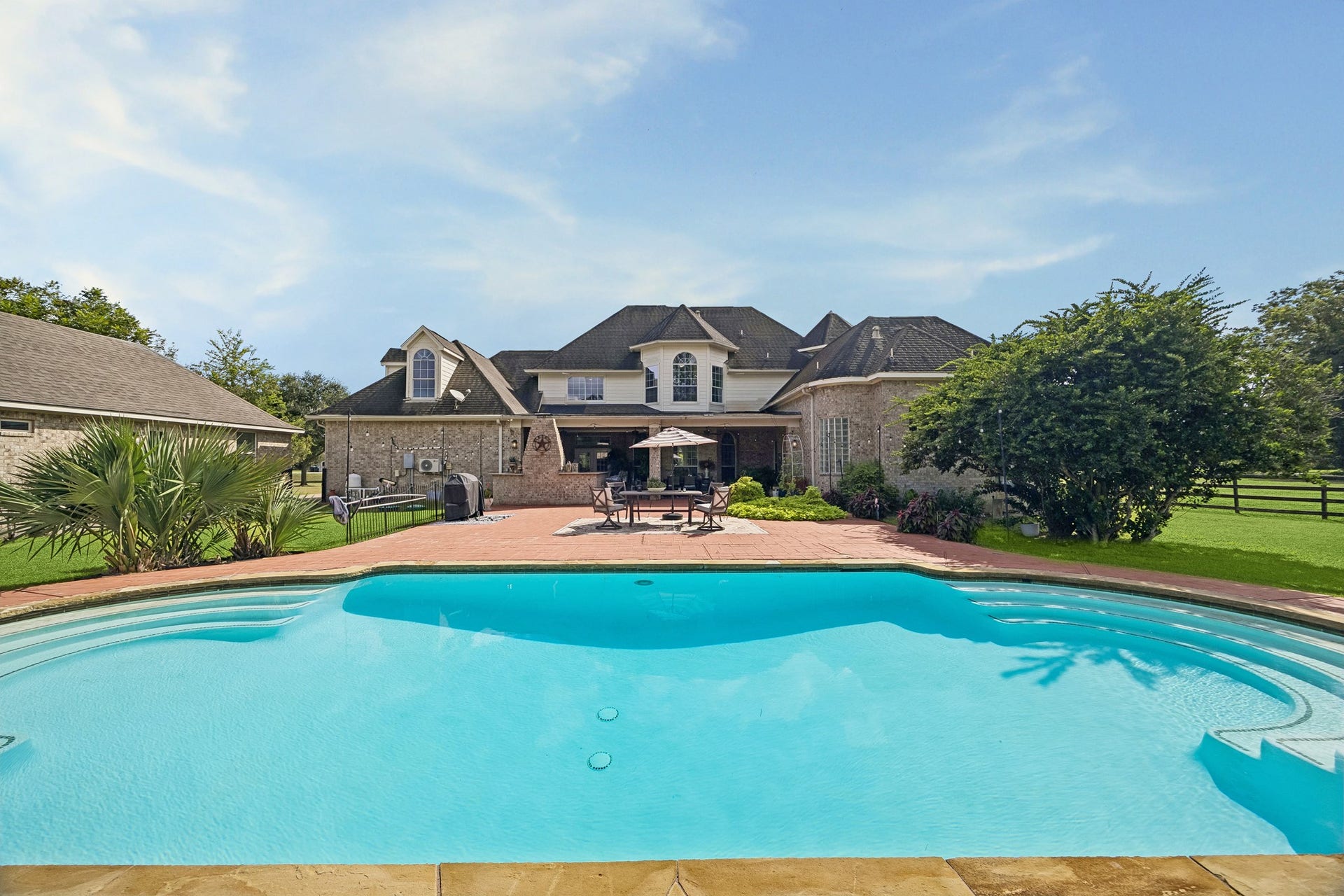 1319 Brazoswood Place, Richmond, TX 77406 A sparkling pool anchors the backyard, complemented by generous patio space, a large covered outdoor living area, and peaceful views of the surrounding acreage. A lifetime of backyard get togethers and enjoyment for all.