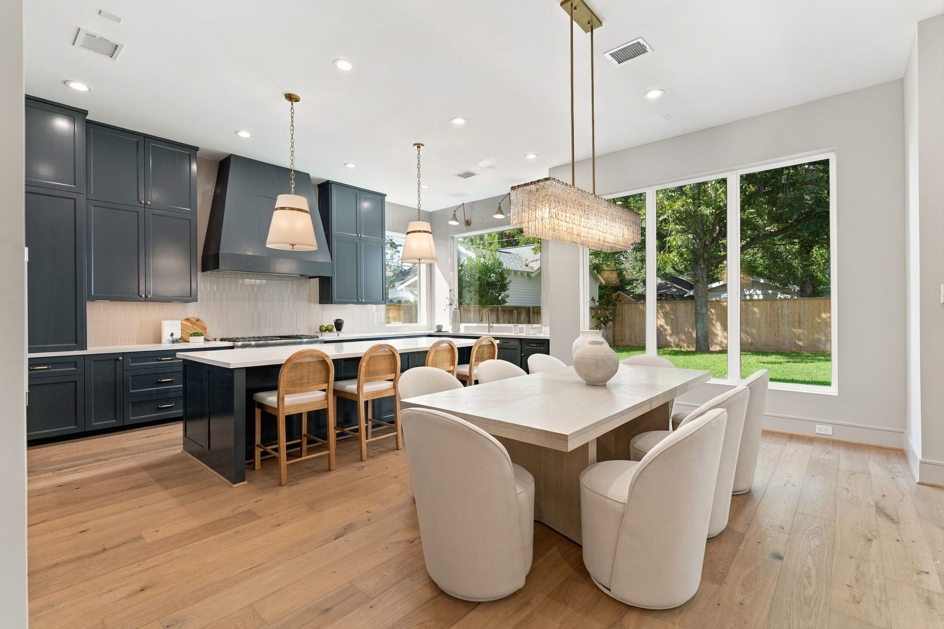 711 E 12th Street, Houston, TX 77008 Gather beneath the striking Z-Lite Glacier chandelier in a dining area framed by oversized windows and backyard views.