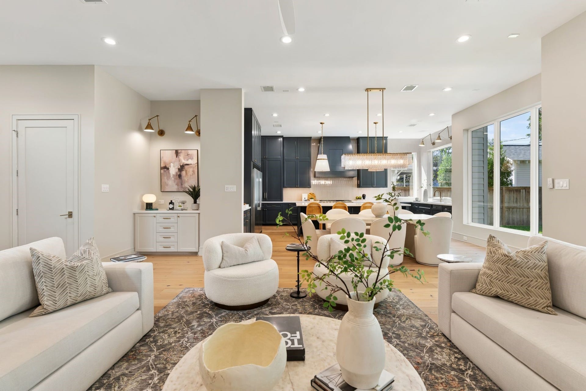 711 E 12th Street, Houston, TX 77008 Bright living-to-kitchen perspective showcasing layered furnishings, designer lighting and an inviting open-plan environment.