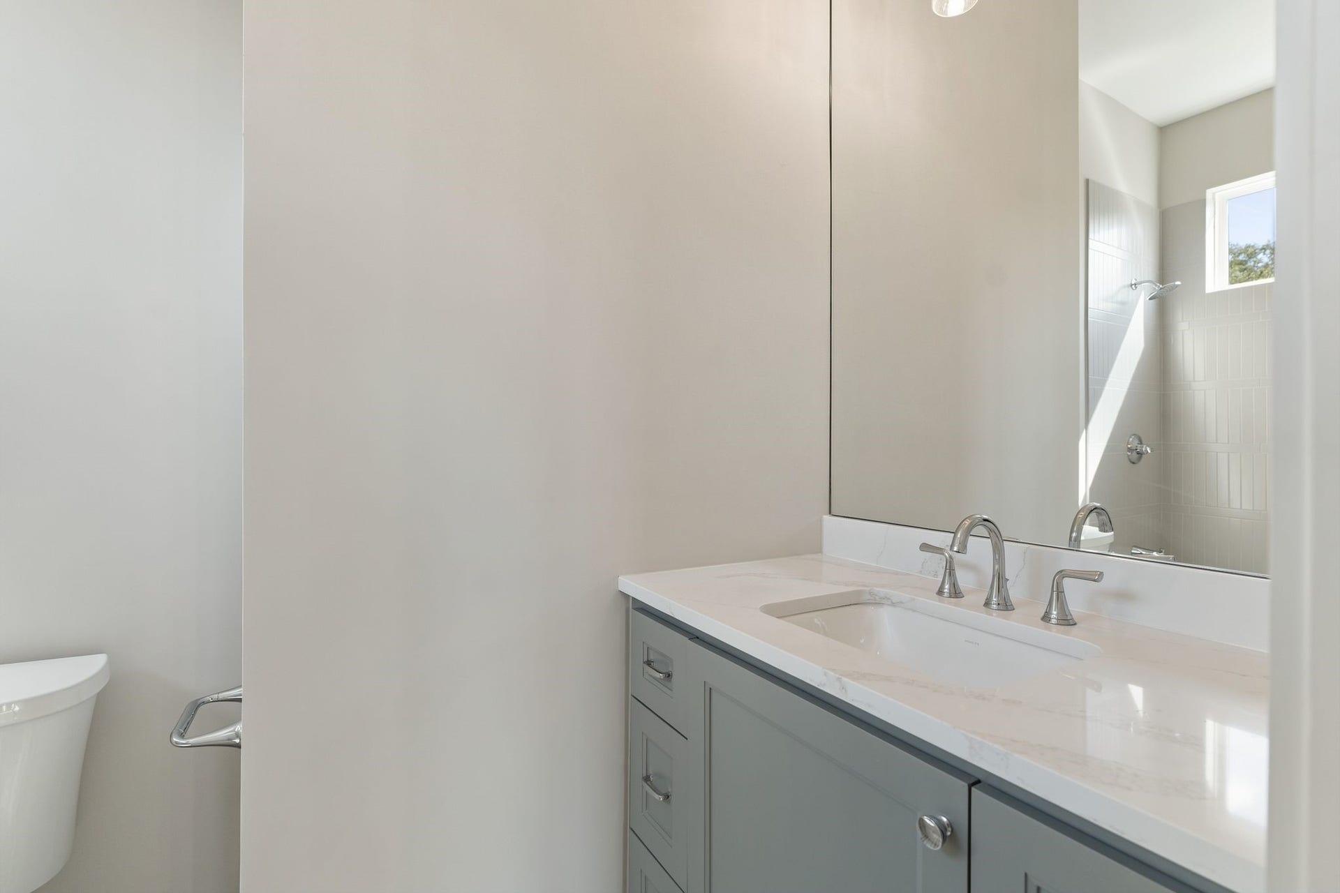 711 E 12th Street, Houston, TX 77008 Sophisticated bath featuring tailored cabinetry, a luminous countertop and polished plumbing fixtures in a serene neutral palette.