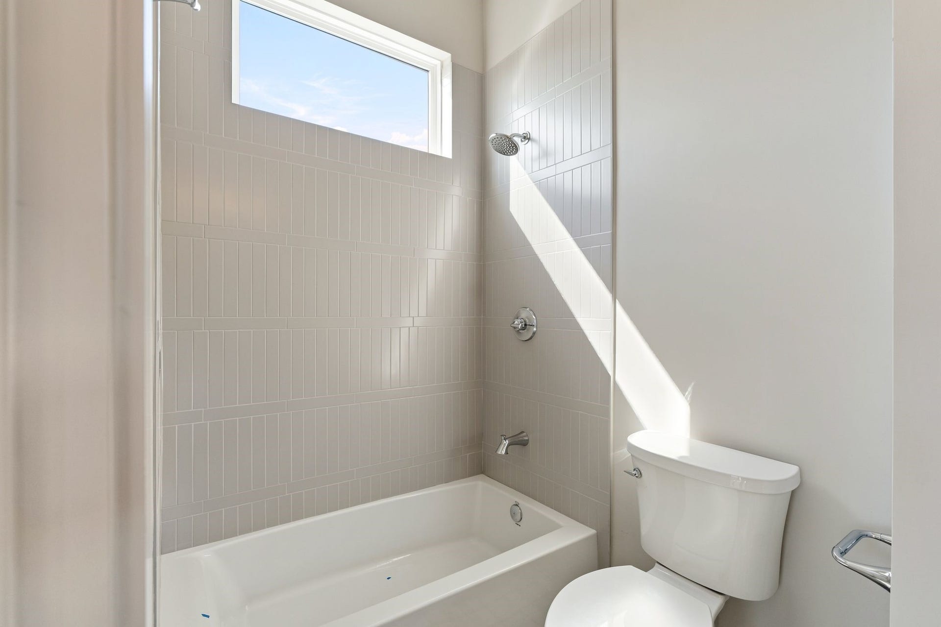 711 E 12th Street, Houston, TX 77008 Classic subway tile and a tartan-inspired floor give this secondary bath a distinctive finish. A bathtub with an overhead shower offers everyday versatility, while a high window welcomes natural light.