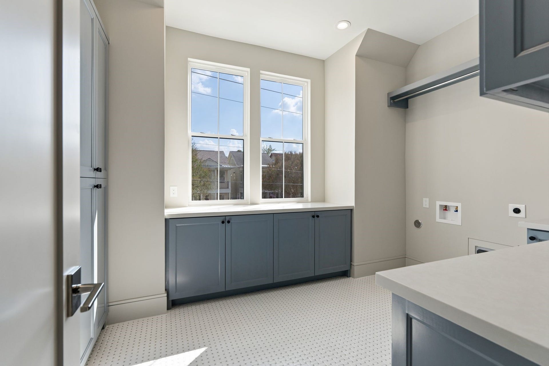 711 E 12th Street, Houston, TX 77008 Sunlight pours into the spacious laundry room, highlighting soft blue cabinetry and charming mosaic floors. Generous quartz counters provide room to sort and fold, while abundant storage keeps everyday essentials neatly tucked away.