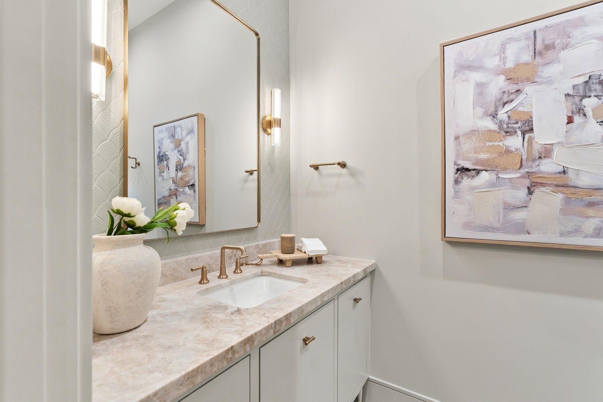 711 E 12th Street, Houston, TX 77008 Soft scalloped tile adds texture to this elegant first-floor bathroom, pairing beautifully with a natural stone countertop and champagne gold hardware. Hinkley Georgette sconces in lacquered brass frame the mirror, while a Delta Saylor faucet completes the vanity.