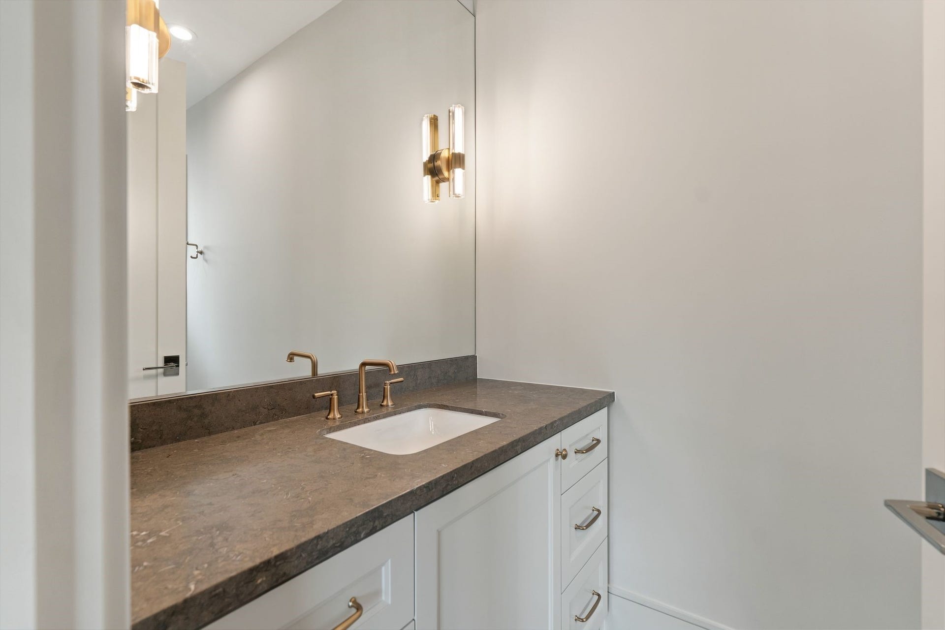 711 E 12th Street, Houston, TX 77008 Well-appointed bath vanity featuring tailored cabinetry, polished fixtures and understated stone-inspired surfaces.