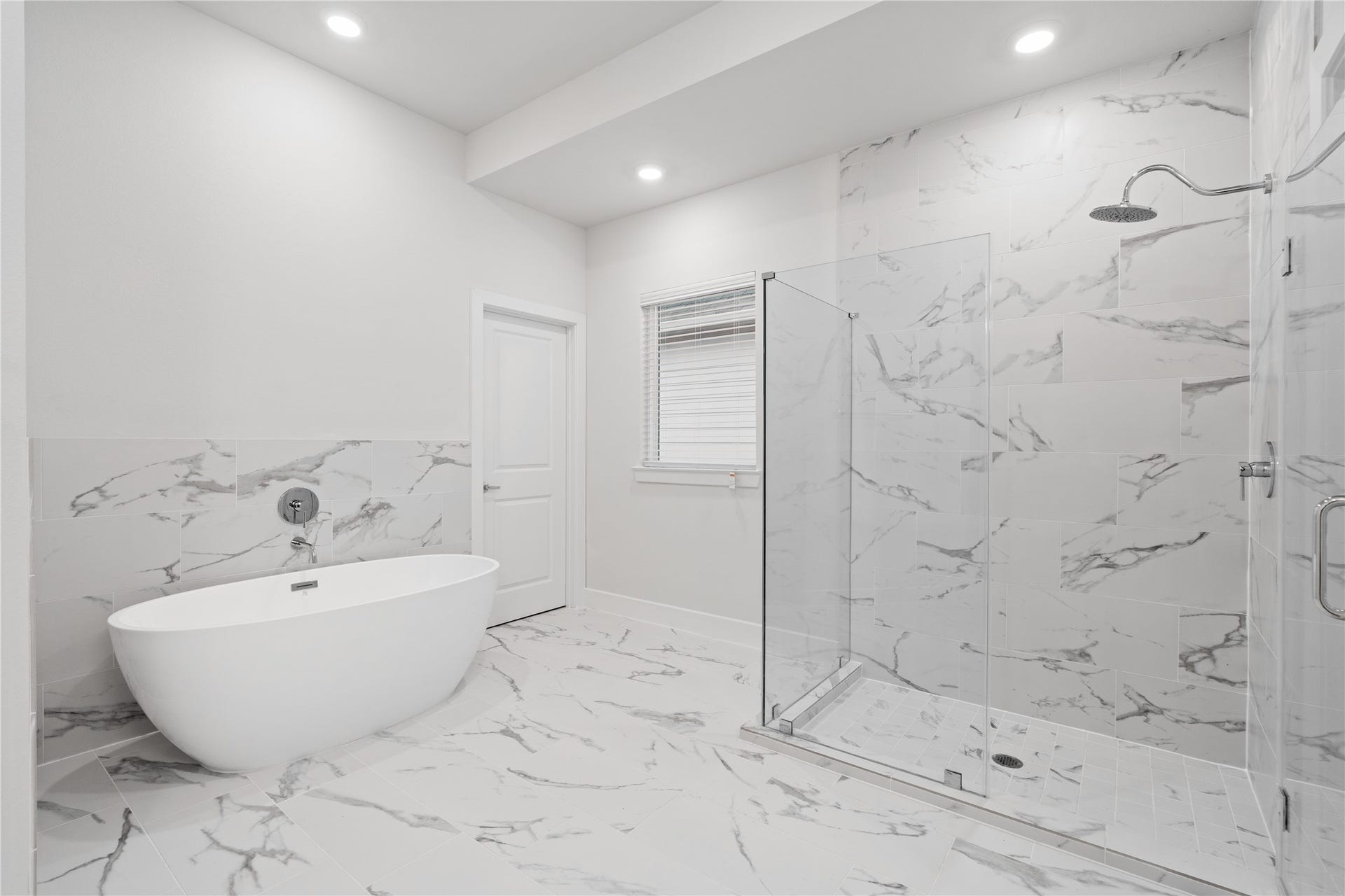 6509 Rena Street, Houston, TX 77092 Freestanding soaking tub positioned across from a glass enclosed shower wrapped in large format tile, creating a layout that feels open rather than compressed.
