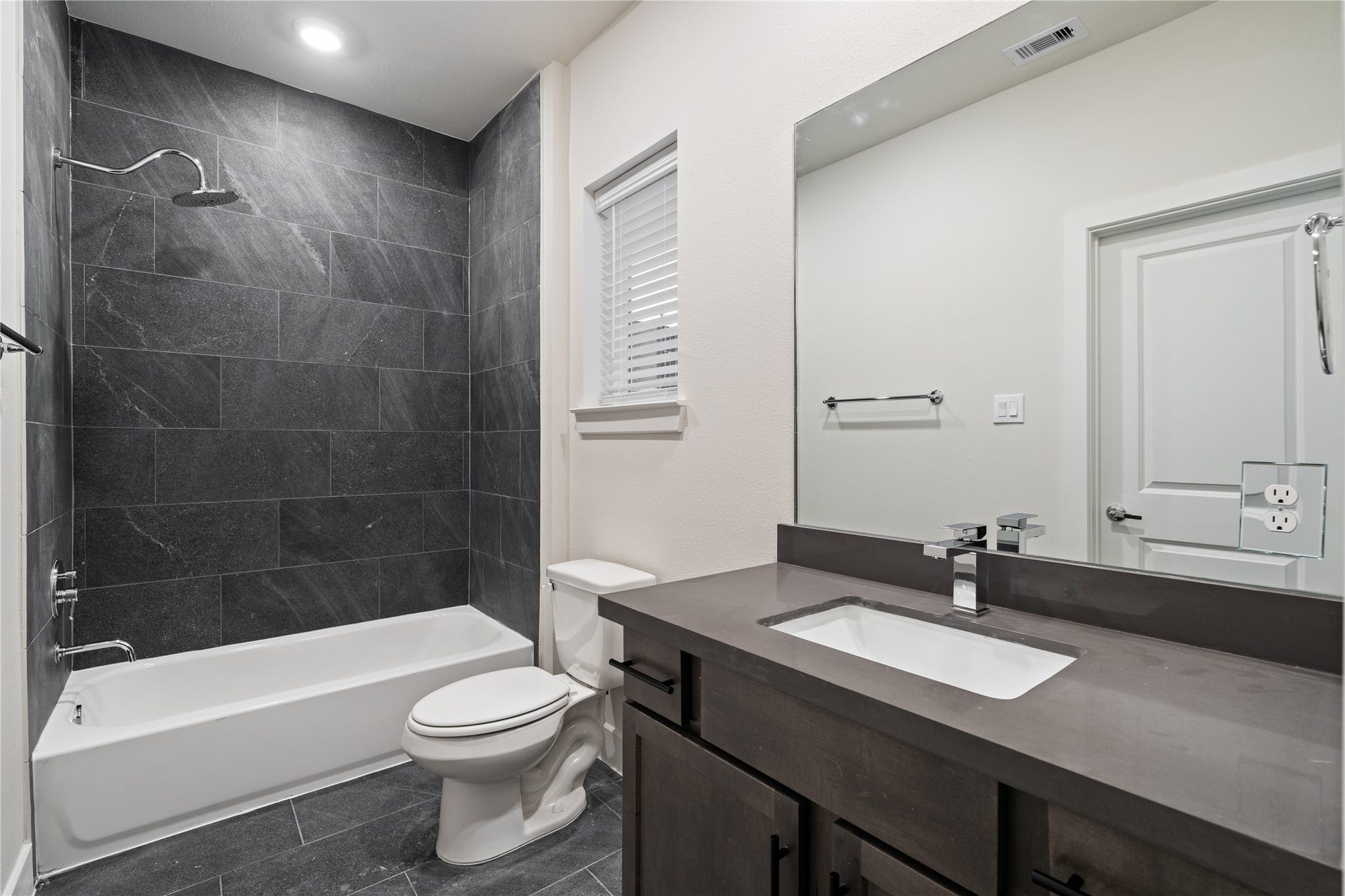 6509 Rena Street, Houston, TX 77092 Secondary bathroom finished with full height dark tile surround and a clean, modern vanity.