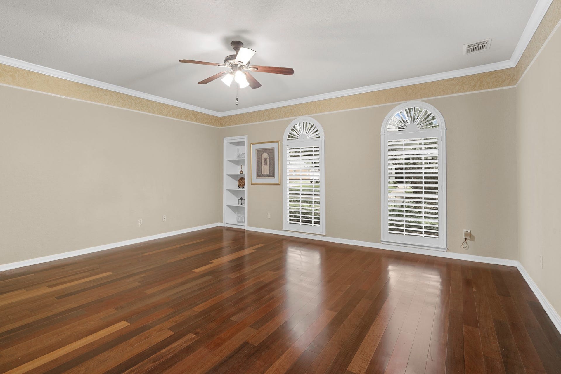 23 Saint Simons Court, Sugar Land, TX 77479 Wood-plank flooring, arched windows, built-in shelves, and crown molding create a stylish and inviting first-floor owner's suite.