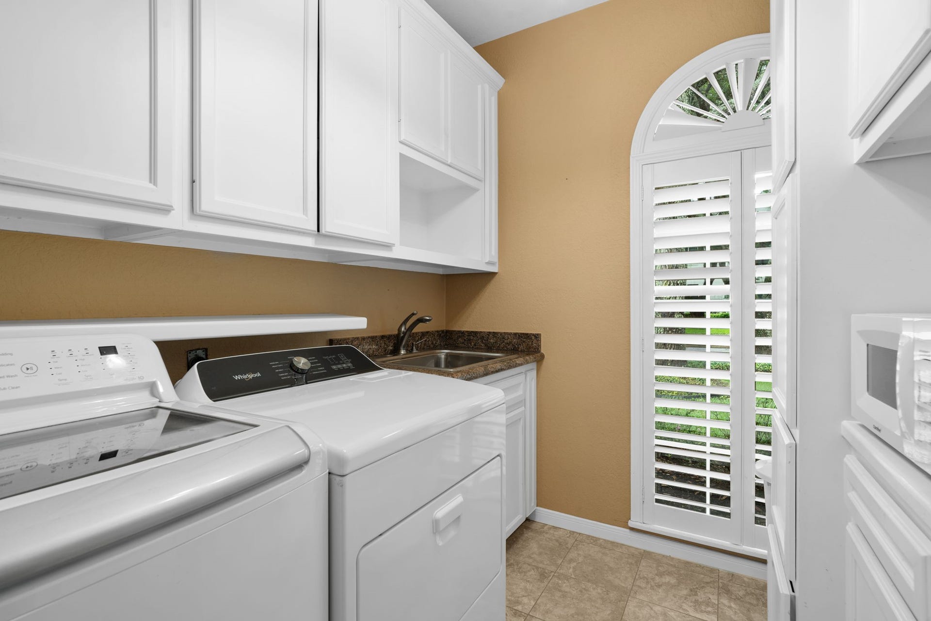 23 Saint Simons Court, Sugar Land, TX 77479 A sink, ample built-in cabinetry, and a large arched window make the laundry room both practical and bright.