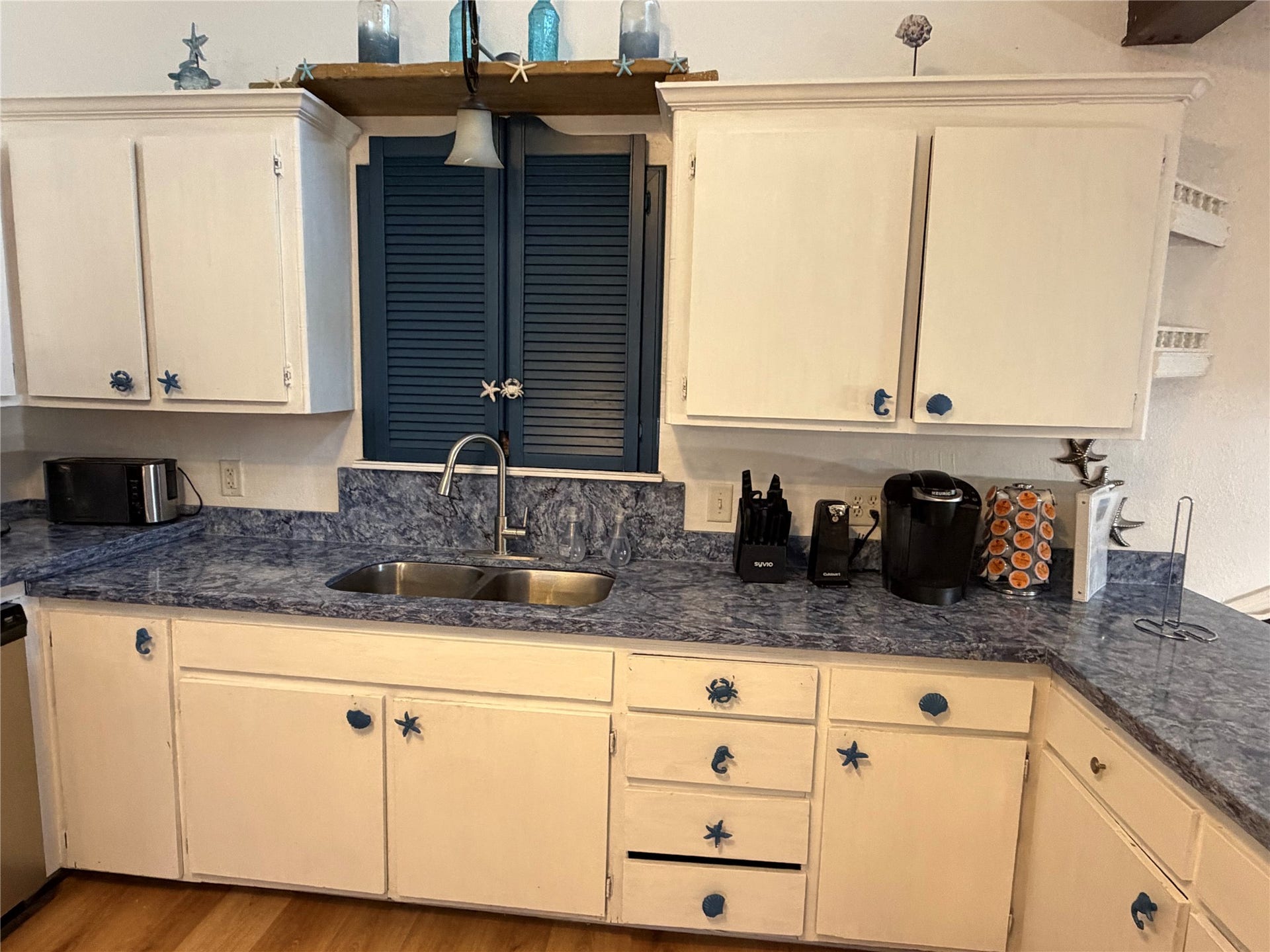 13002 Buccaneer Parkway, Freeport, TX 77541 Charming kitchen with ample cabinetry, a convenient spice cabinet above the sink, and elegant countertops for a stylish and functional space.