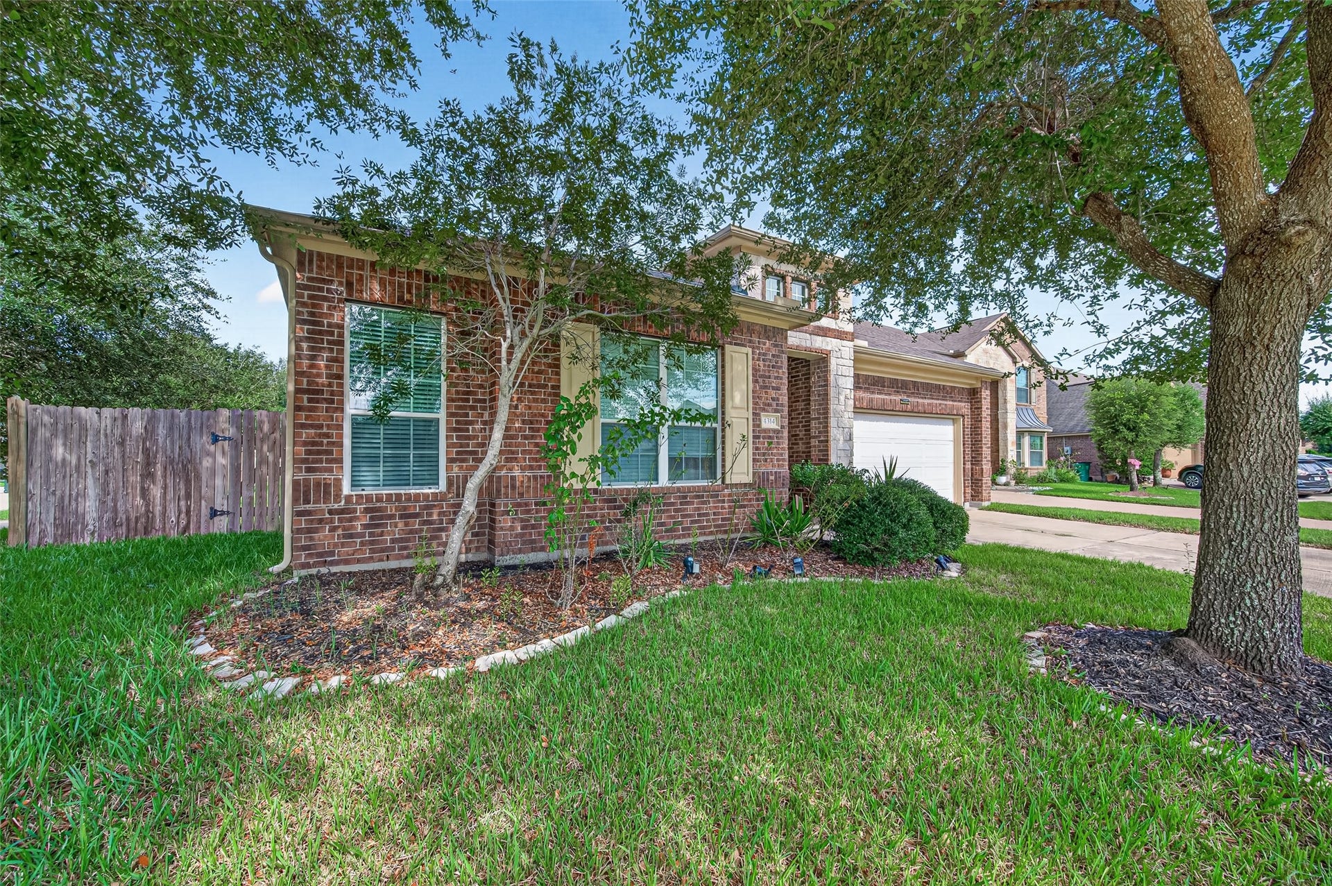 4314 Kent Ranch Court, Katy, TX 77494 Side view of the front with mature trees, curbed landscape beds and a wood privacy fence.