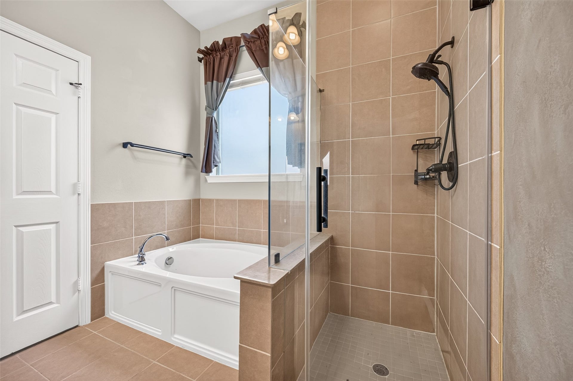 4314 Kent Ranch Court, Katy, TX 77494 Garden tub with tile surround next to a tiled walk-in shower with built-in niche.