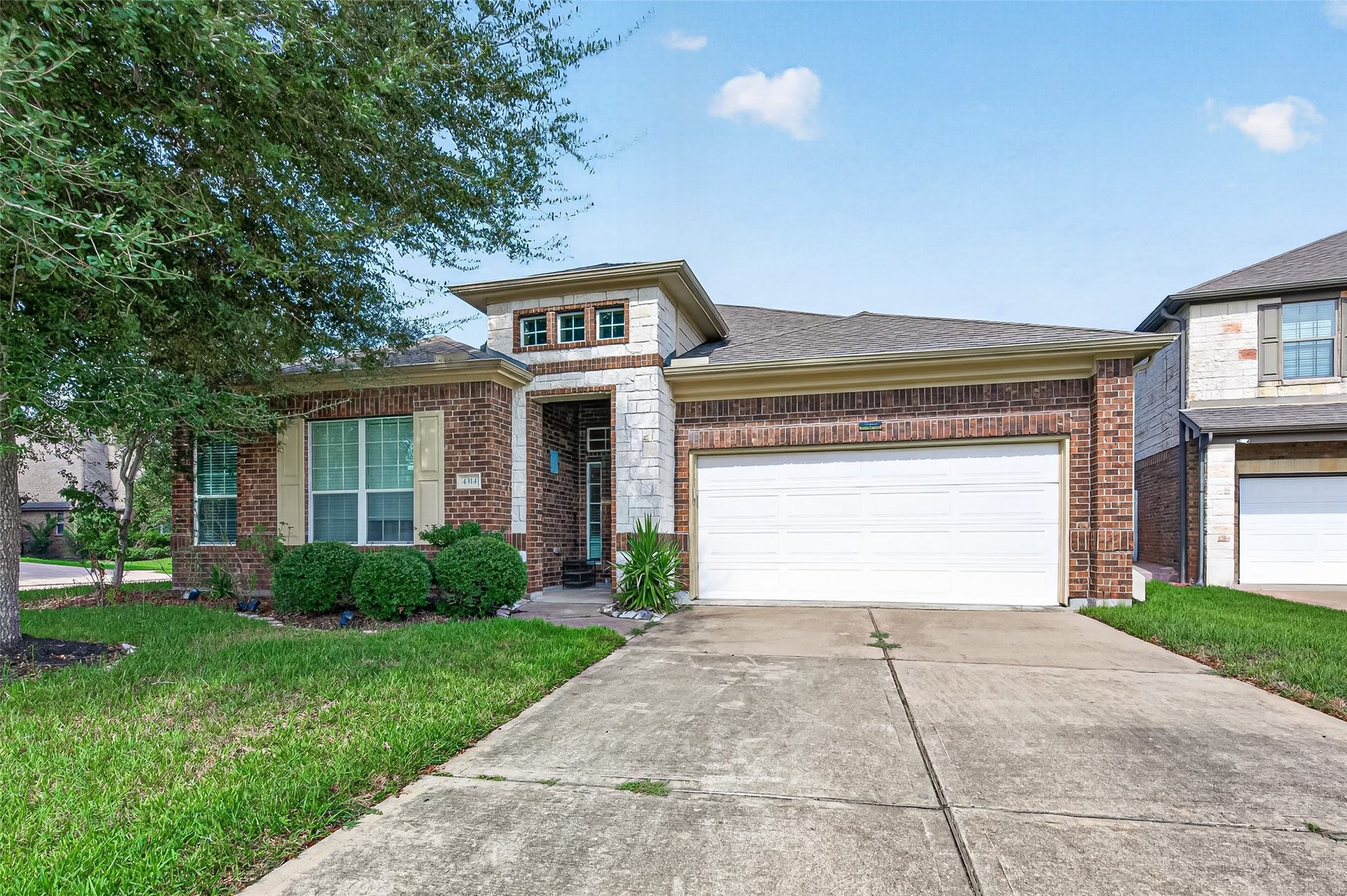 4314 Kent Ranch Court, Katy, TX 77494 Brick and stone front exterior with an extended driveway, two-car garage and landscaped beds.