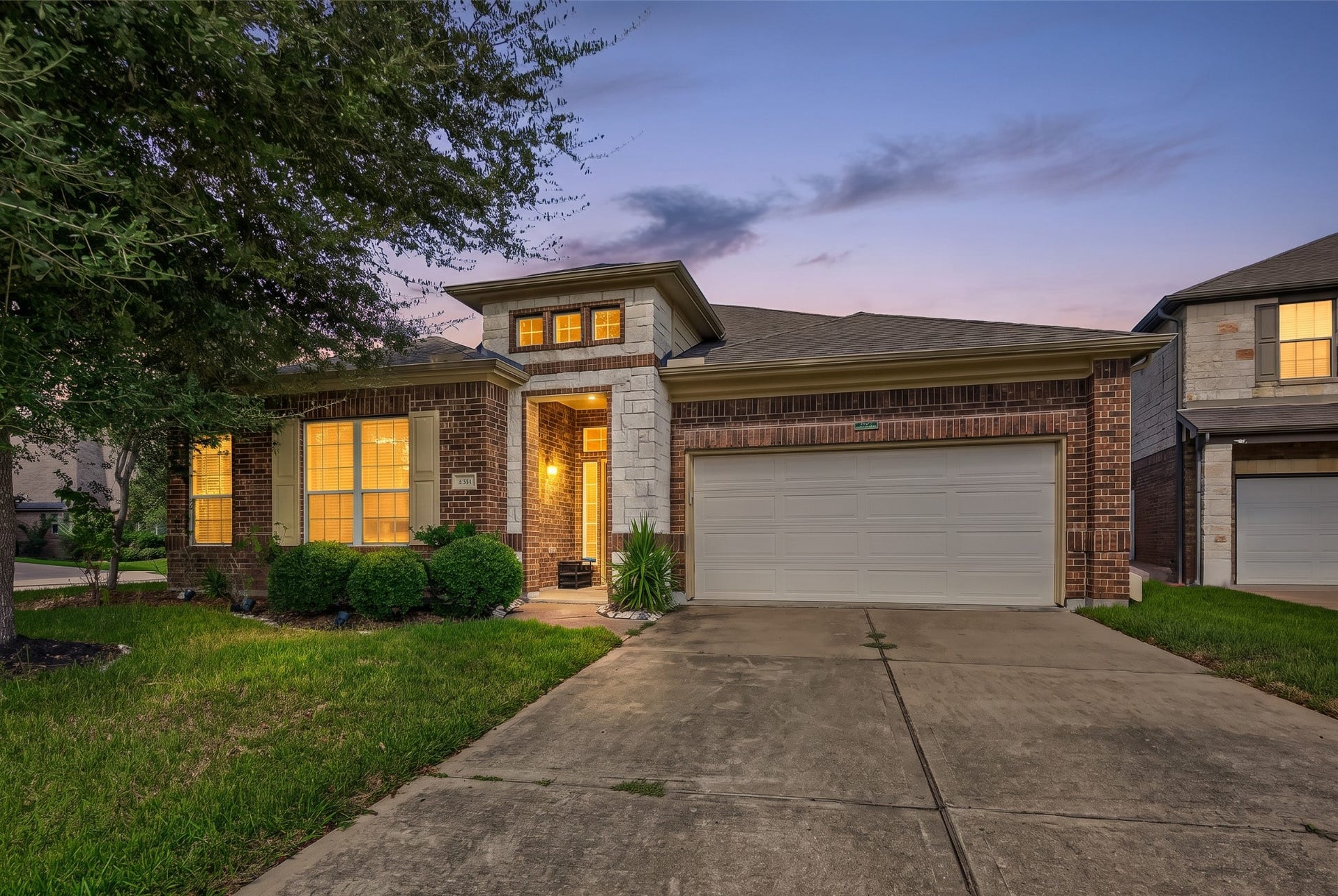 4314 Kent Ranch Court, Katy, TX 77494 Virtually enhanced twilight photo. One-story brick and stone home with a cast-stone entry tower, two-car garage and mature shade tree.