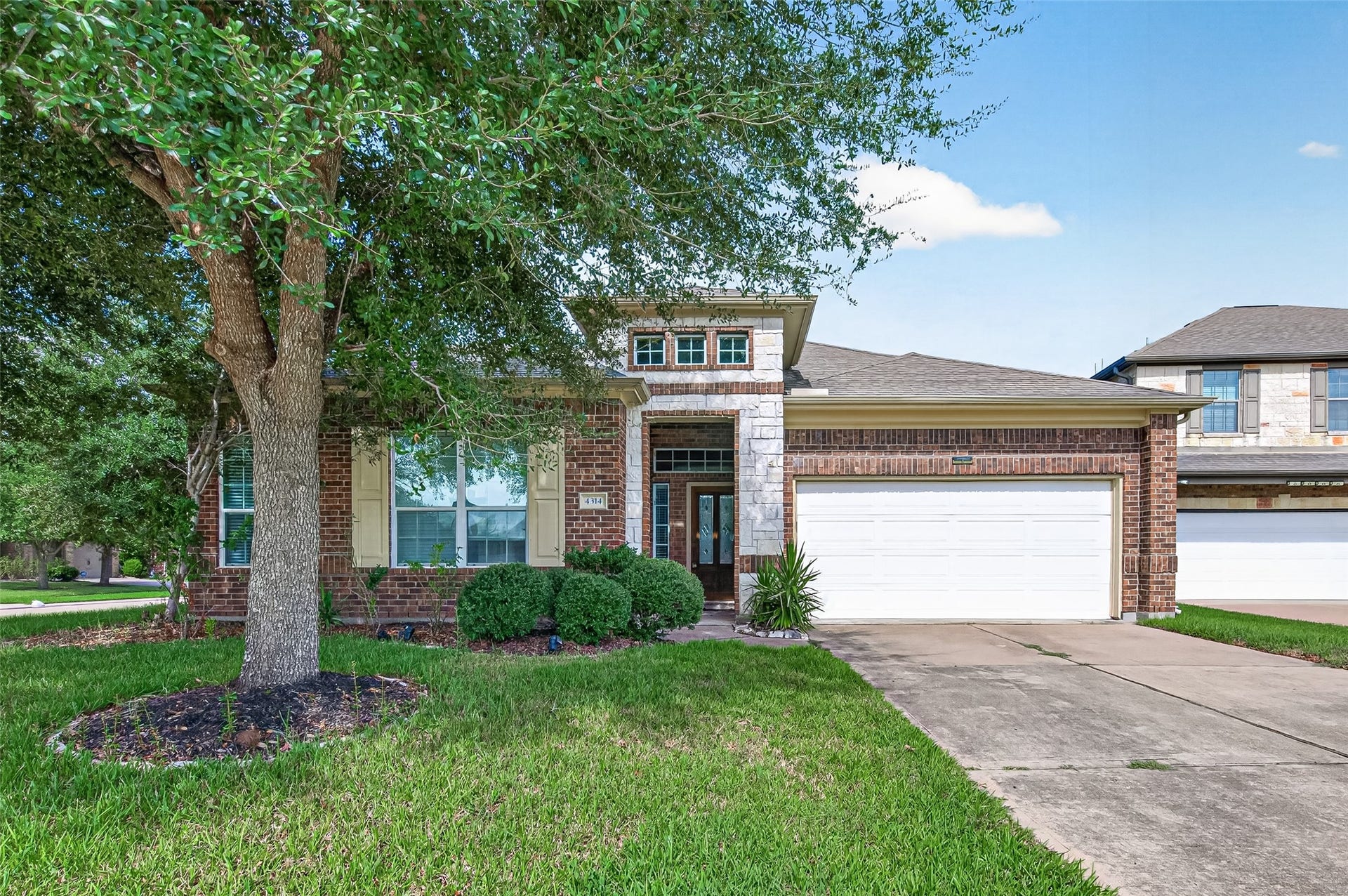4314 Kent Ranch Court, Katy, TX 77494 Front view framed by a mature shade tree, with mulched tree ring and shrubs along the front.