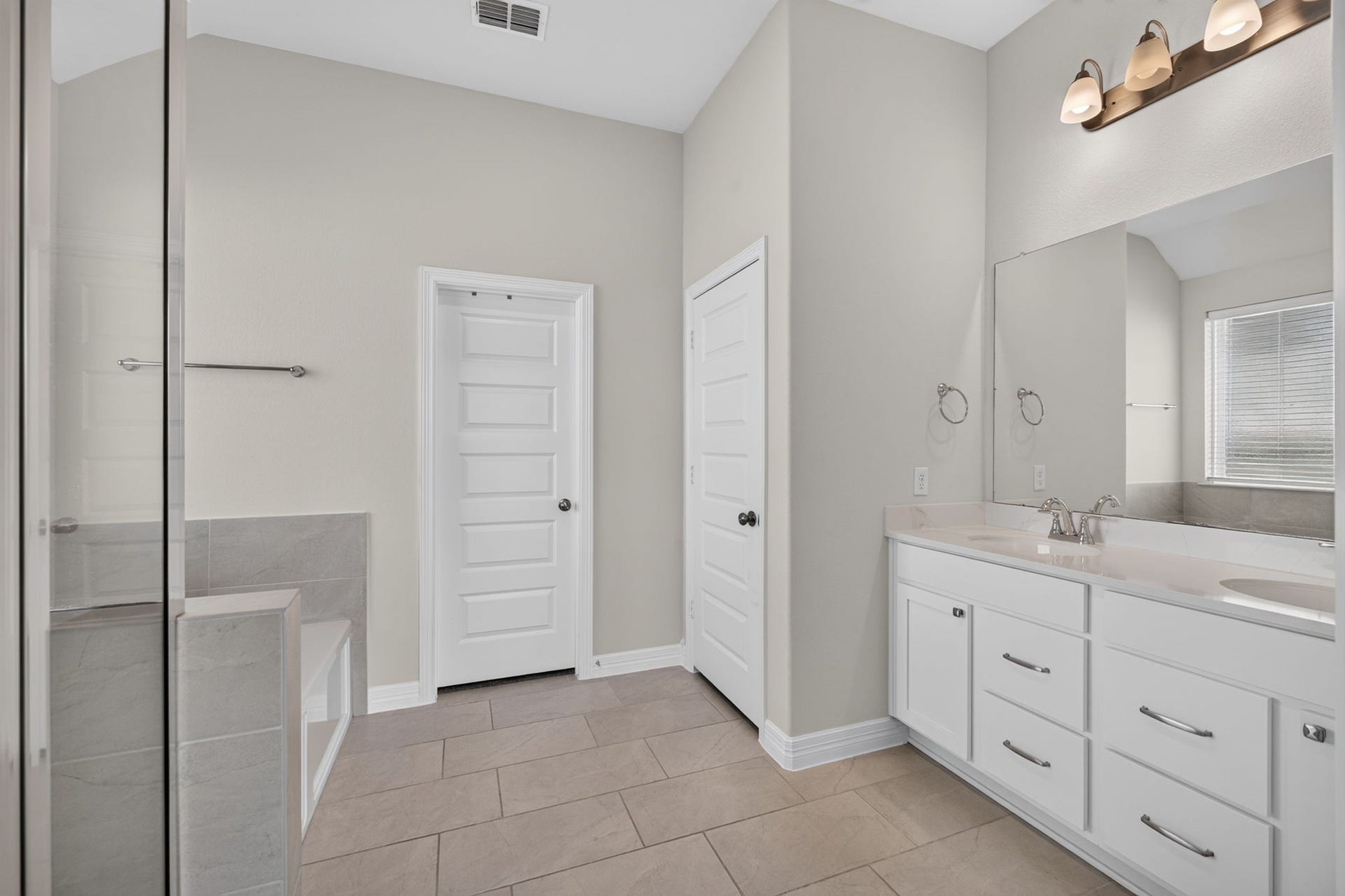 24638 Carleton Lake Lane, Tomball, TX 77375 Primary bath has dual vanities, a large soaking tub, and glass-enclosed shower.