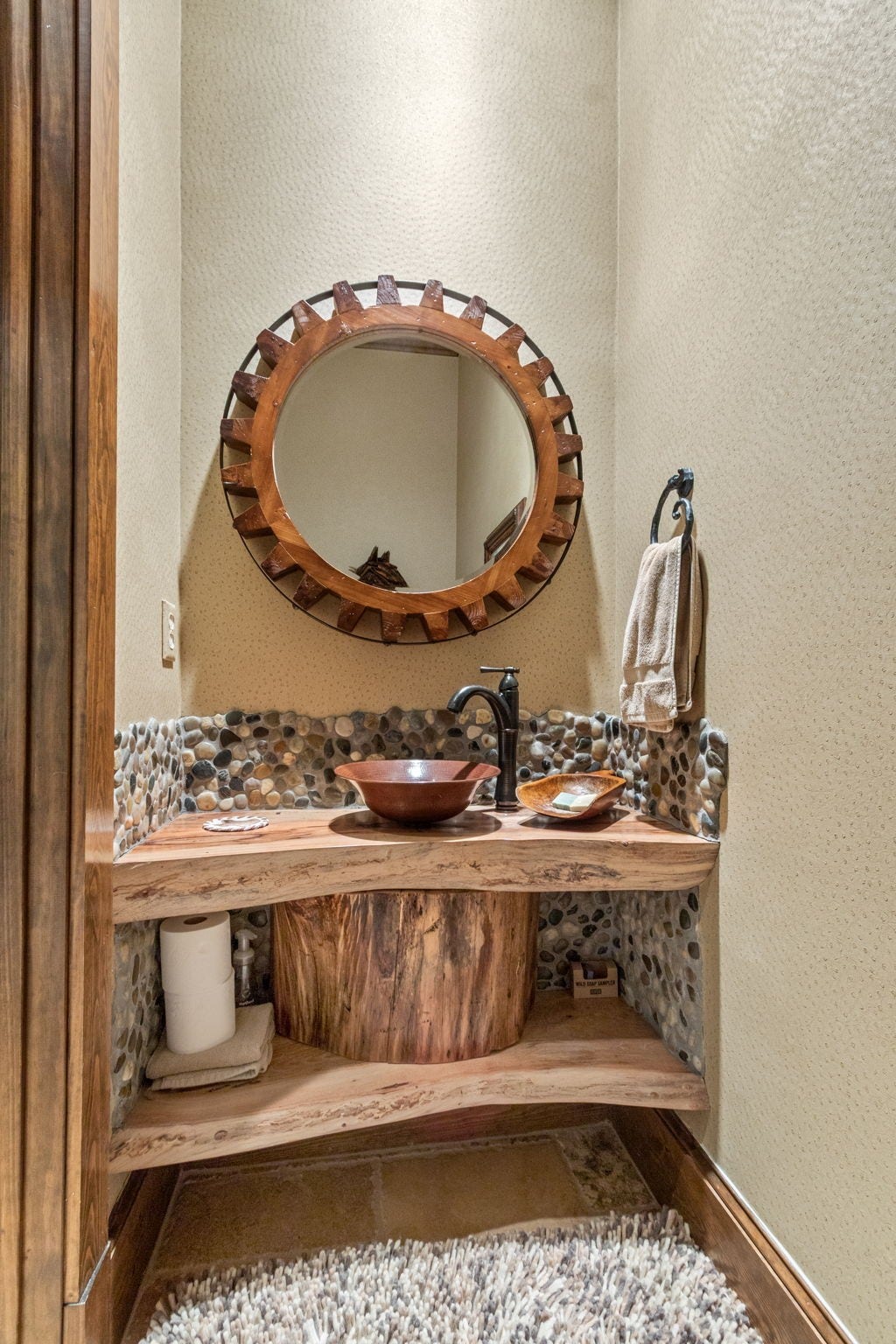 23107 Kobs Road, Tomball, TX 77377 This cozy bathroom features a rustic wooden vanity with a vessel sink and a pebble backsplash. A unique round mirror adds charm.