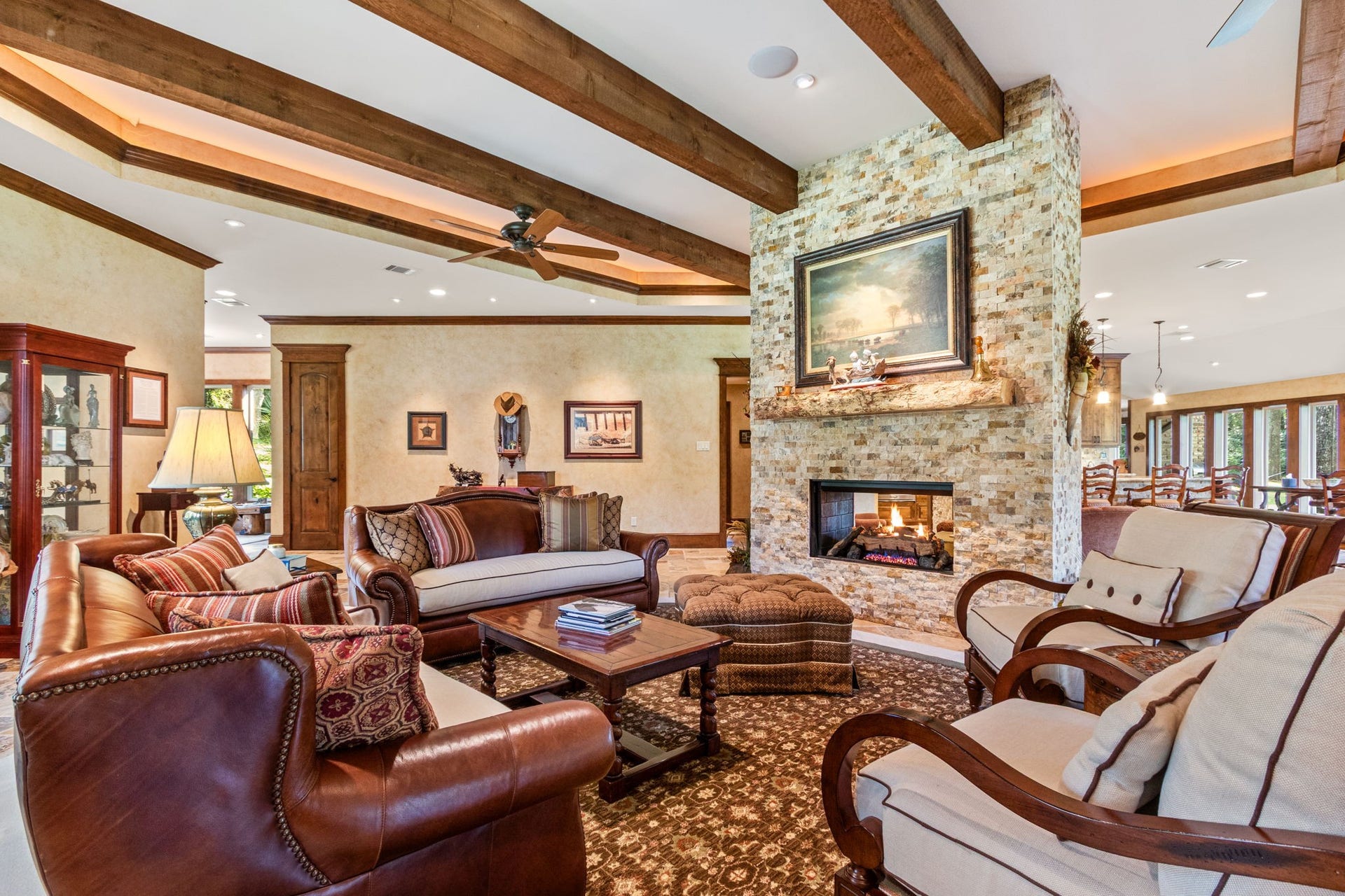 23107 Kobs Road, Tomball, TX 77377 his spacious living area features elegant wooden beams and a cozy stone fireplace. It offers plenty of room for your furniture, warm lighting, and a seamless flow into the dining area, creating an inviting atmosphere ideal for relaxation and entertaining.