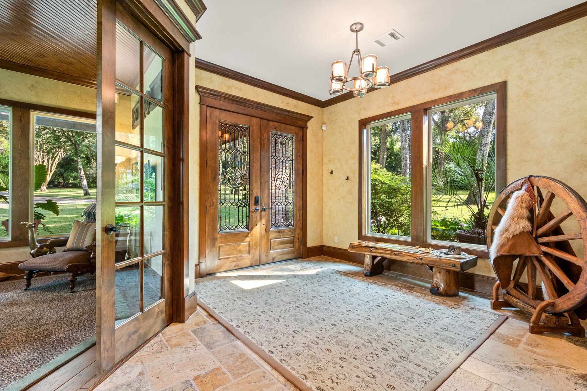 23107 Kobs Road, Tomball, TX 77377 This inviting entryway features elegant wooden double doors with intricate glass designs and a large window offering scenic views of the lush greenery outside. Beautiful chandelier, crown molding, and tile flooring will welcome your guests!