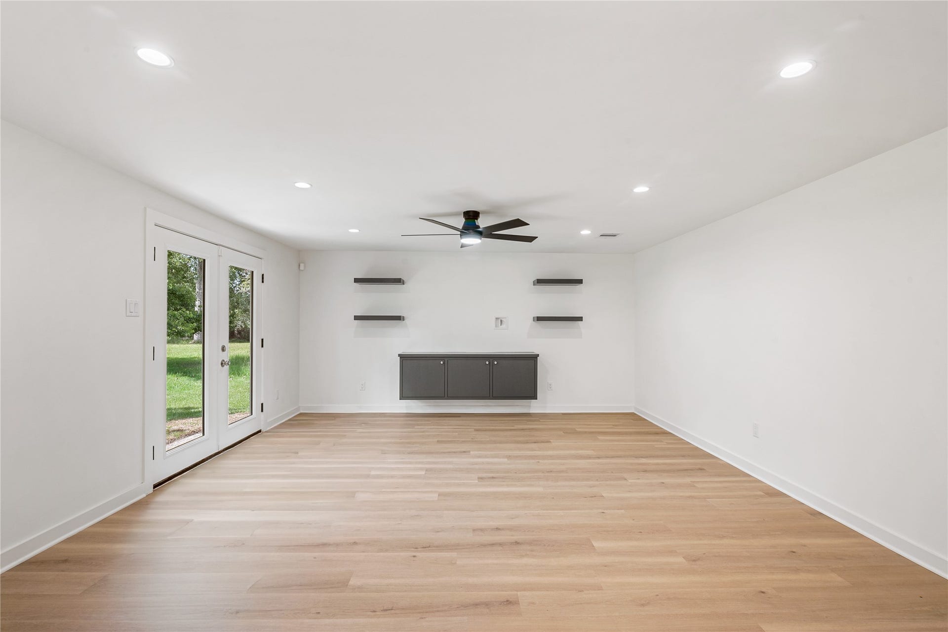 703 Newton Drive, Richmond, TX 77469 Generously sized living room features a contemporary ceiling fan, recessed lighting, and a sleek fireplace accent wall.
