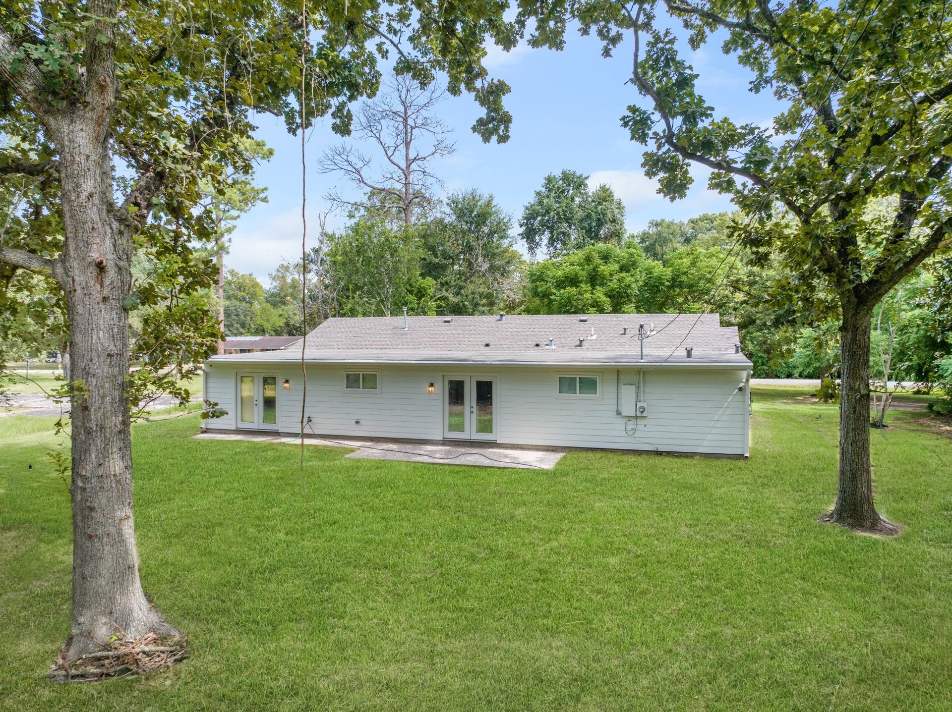 703 Newton Drive, Richmond, TX 77469 Side view of the home framed by mature shade trees and expansive lawn, highlighting the property's spacious setting.
