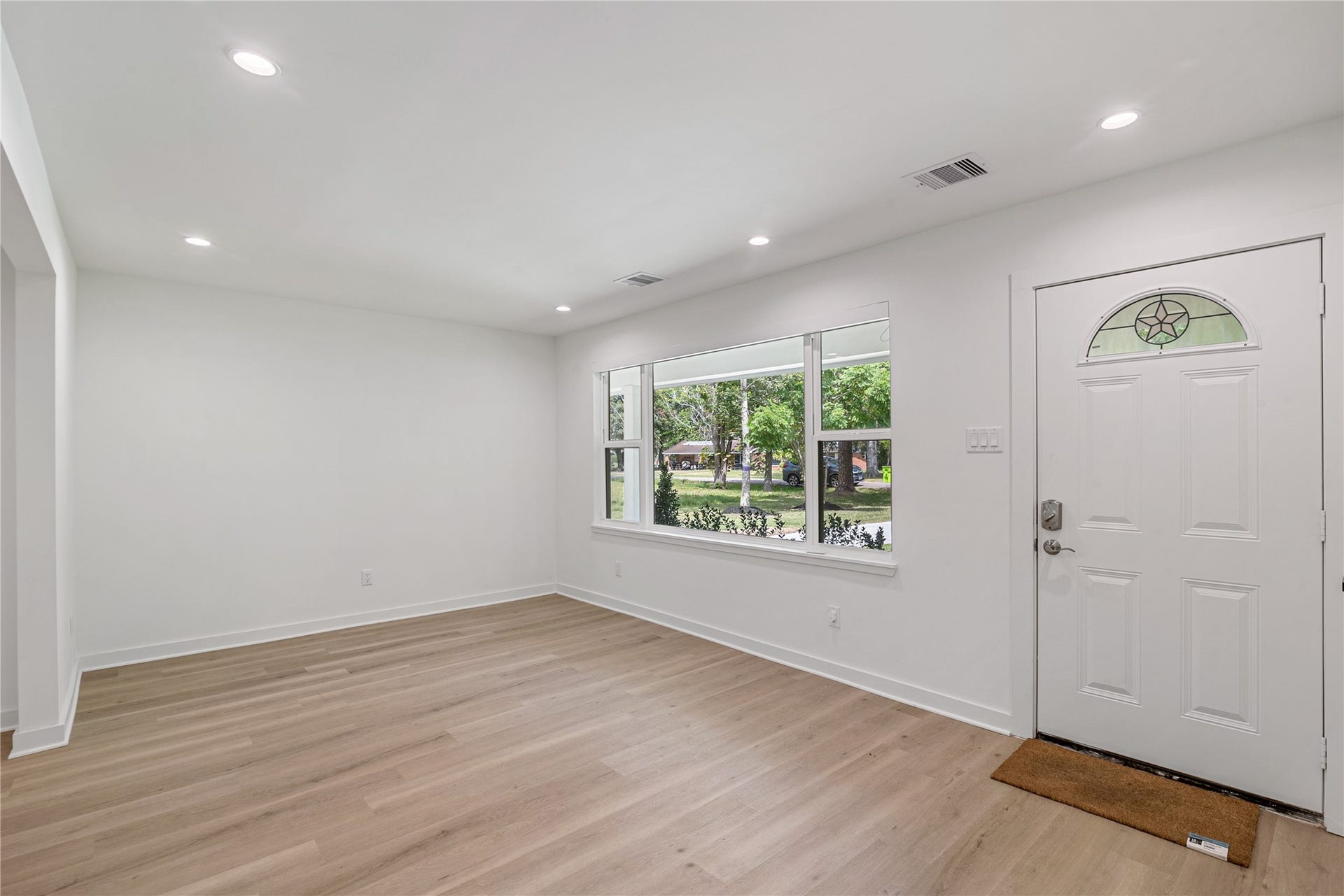 703 Newton Drive, Richmond, TX 77469 Welcoming front living area with updated flooring, recessed lighting, and a large window overlooking the front lawn.