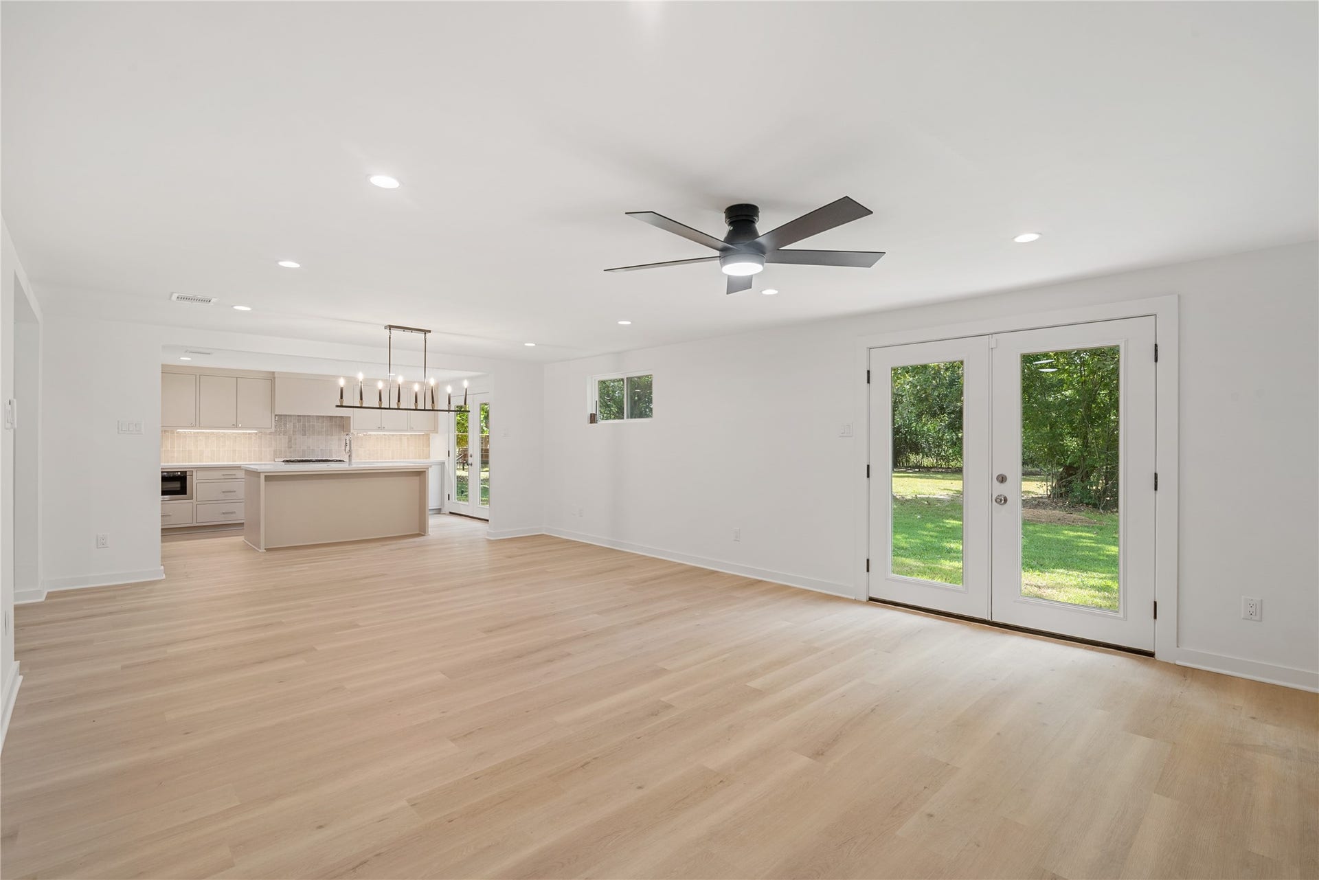 703 Newton Drive, Richmond, TX 77469 Open living room offers plenty of room to gather, with a modern ceiling fan and glass doors opening to the outdoor space.
