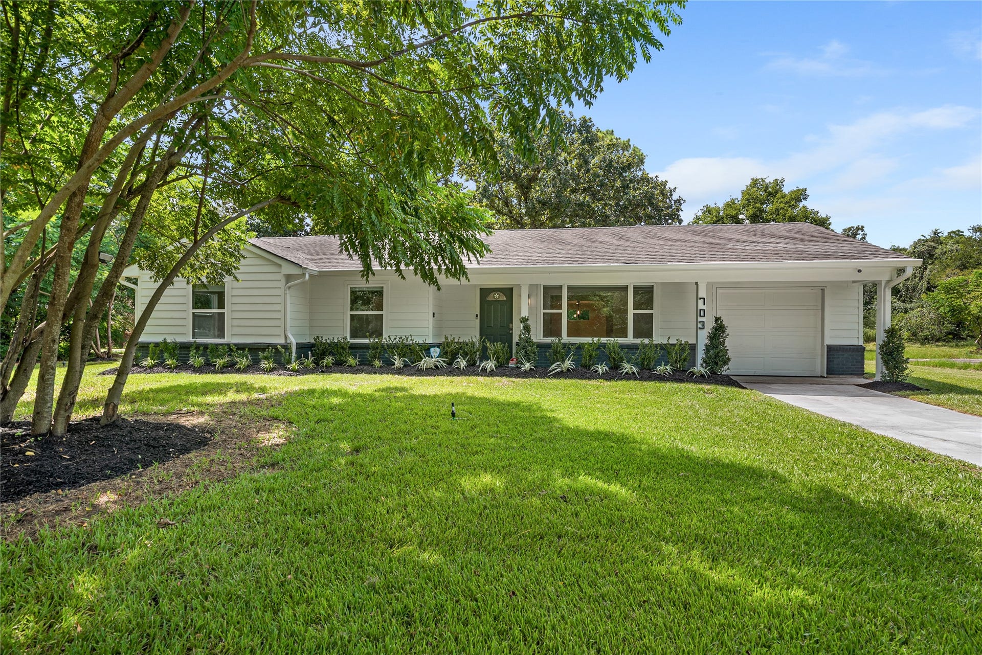 703 Newton Drive, Richmond, TX 77469 Inviting front exterior showcasing the home's refreshed appearance, mature landscaping, and spacious front lawn.