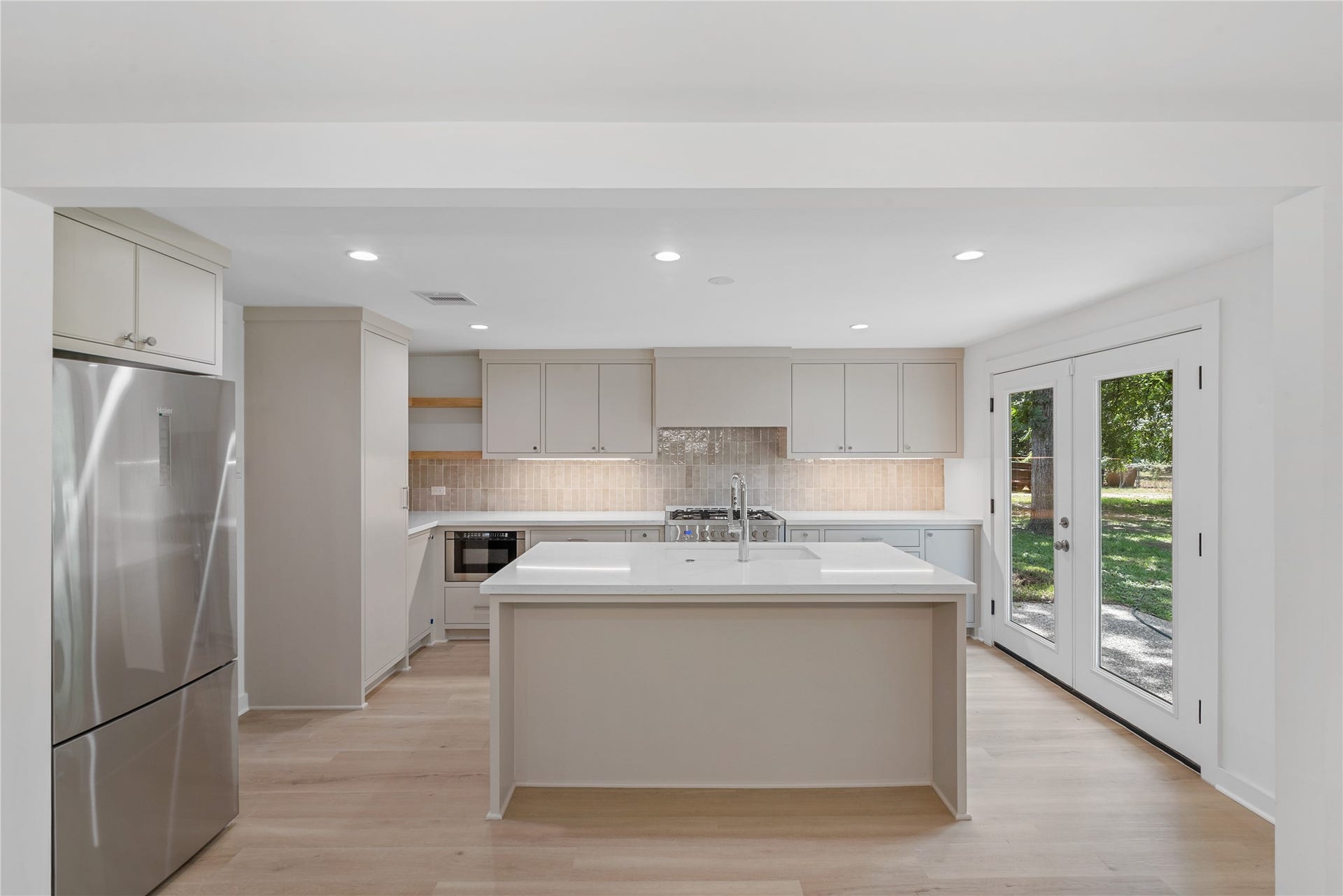 703 Newton Drive, Richmond, TX 77469 Beautifully updated kitchen featuring a large quartz-topped island, stainless steel appliances, custom cabinetry, and recessed lighting.