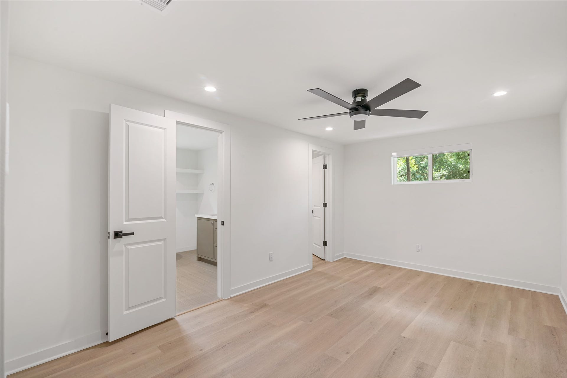 703 Newton Drive, Richmond, TX 77469 Spacious bedroom featuring updated flooring, a contemporary ceiling fan, and a window overlooking the greenery outside.