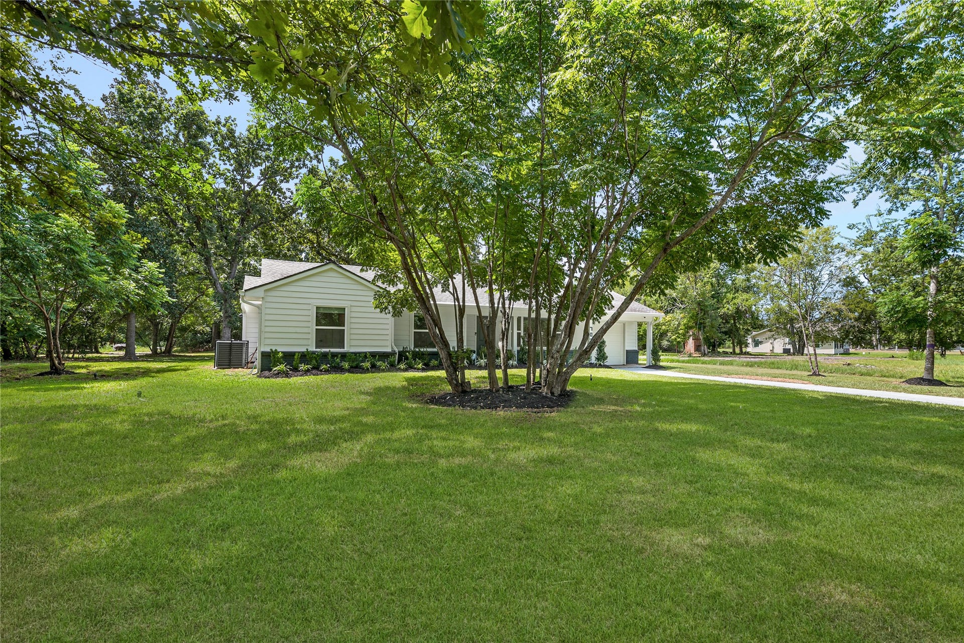 703 Newton Drive, Richmond, TX 77469 Expansive, tree-lined front lawn highlights the generous lot size and peaceful, established surroundings.