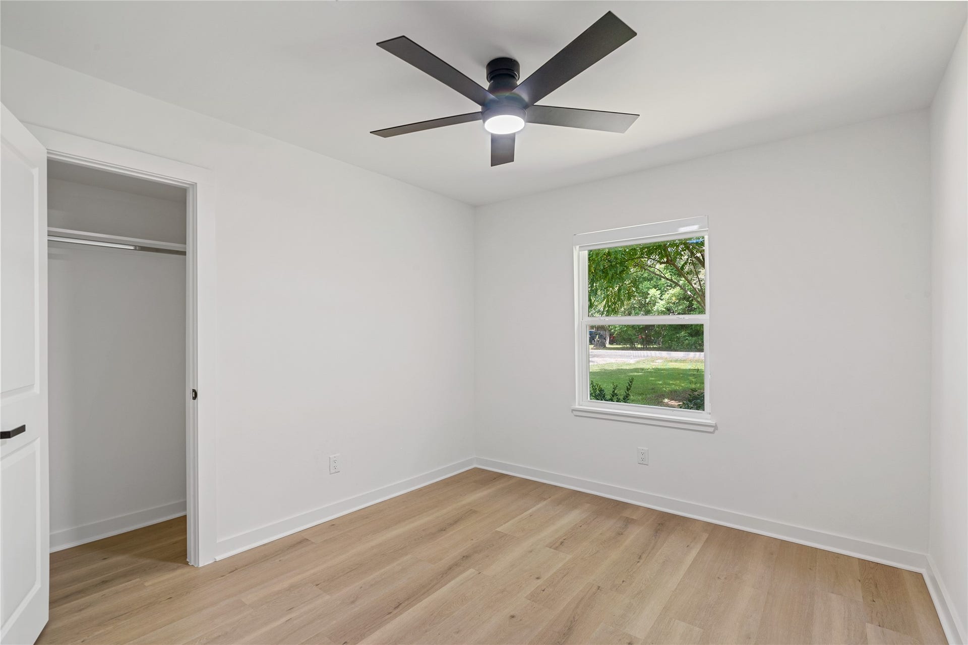 703 Newton Drive, Richmond, TX 77469 Bright secondary bedroom with updated flooring, a modern ceiling fan, and a window providing natural light.