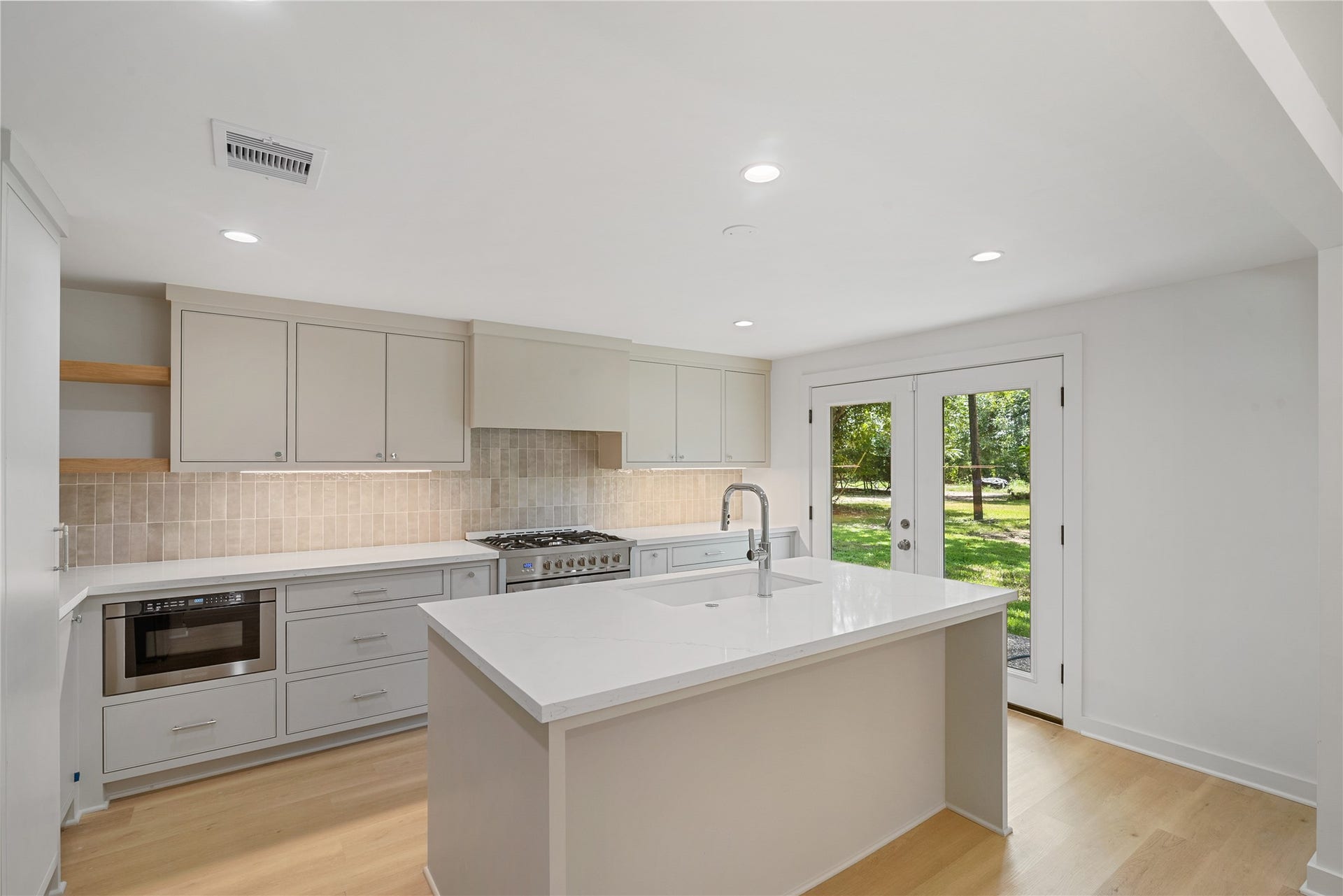 703 Newton Drive, Richmond, TX 77469 Additional kitchen view highlighting the quartz countertops, sleek finishes, and natural light from the adjoining exterior doors.