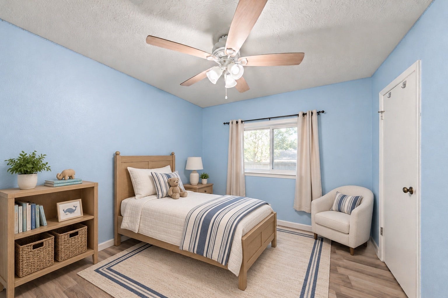 This Secondary Bedroom (10'3" x 9'0") has a ceiling fan with light and a window with curtains already hung. A bed and a reading chair fit with room left for a bookshelf, and open floor stays clear between the bed and the door. Wood-look flooring runs through, with light blue walls and white trim. The room opens off the bedroom hall near the Living Room. Its size also works well as a home office or guest room, with a desk under the window! Virtually staged.