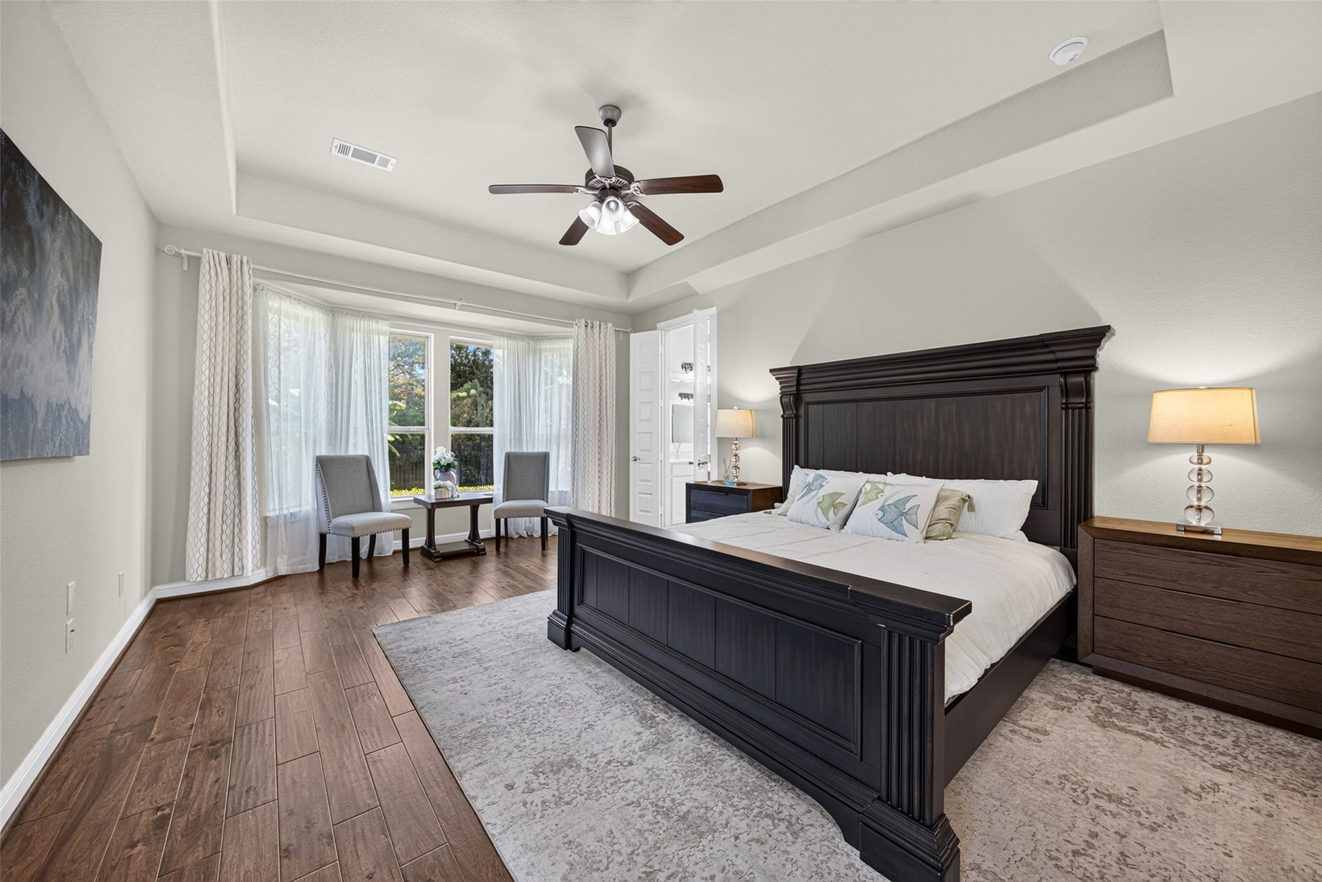 5811 Caper Shores Lane, Sugar Land, TX 77479 The spacious primary bedroom features rich wood floors, a tray ceiling, and a bright sitting area framed by expansive windows.