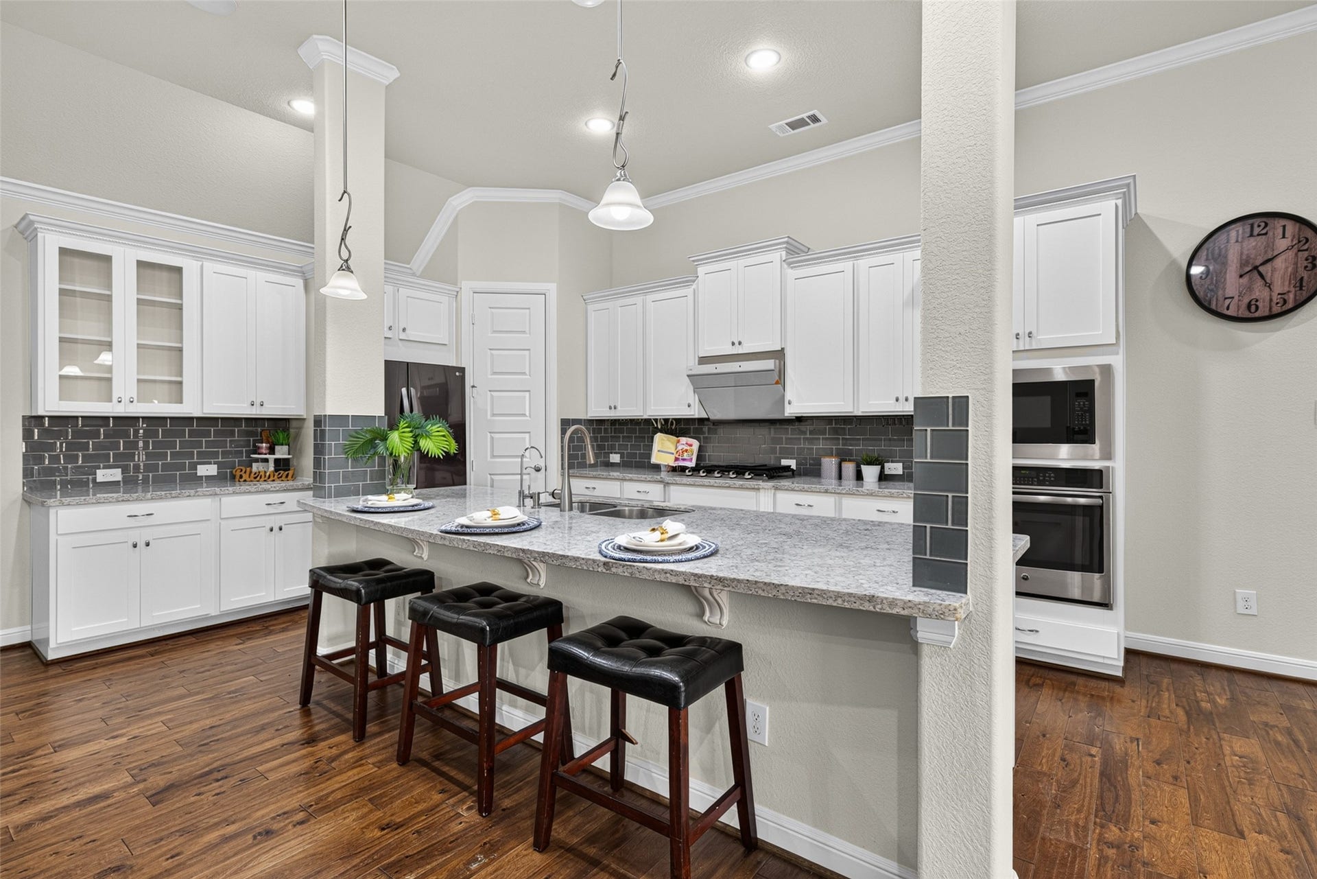 5811 Caper Shores Lane, Sugar Land, TX 77479 The well-appointed kitchen features a generous granite island countertop, stainless steel appliances, crisp white cabinetry, and a chic tile backsplash.