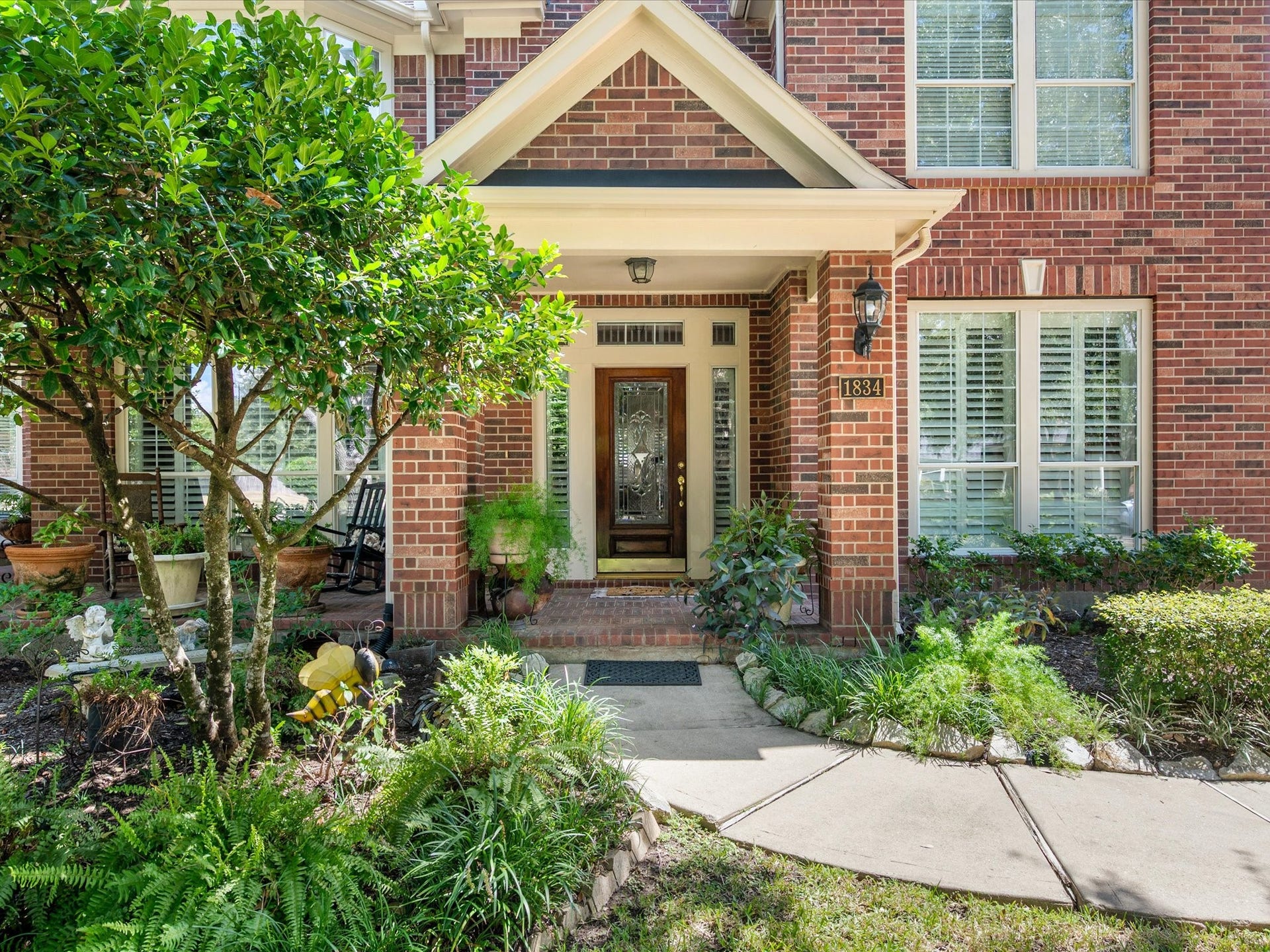 1834 Lake Quitman Drive, Richmond, TX 77406 Elegant glass and wood front door framed by sidelights, a gabled portico, and rich brick detail, with a paver walkway welcoming you home.