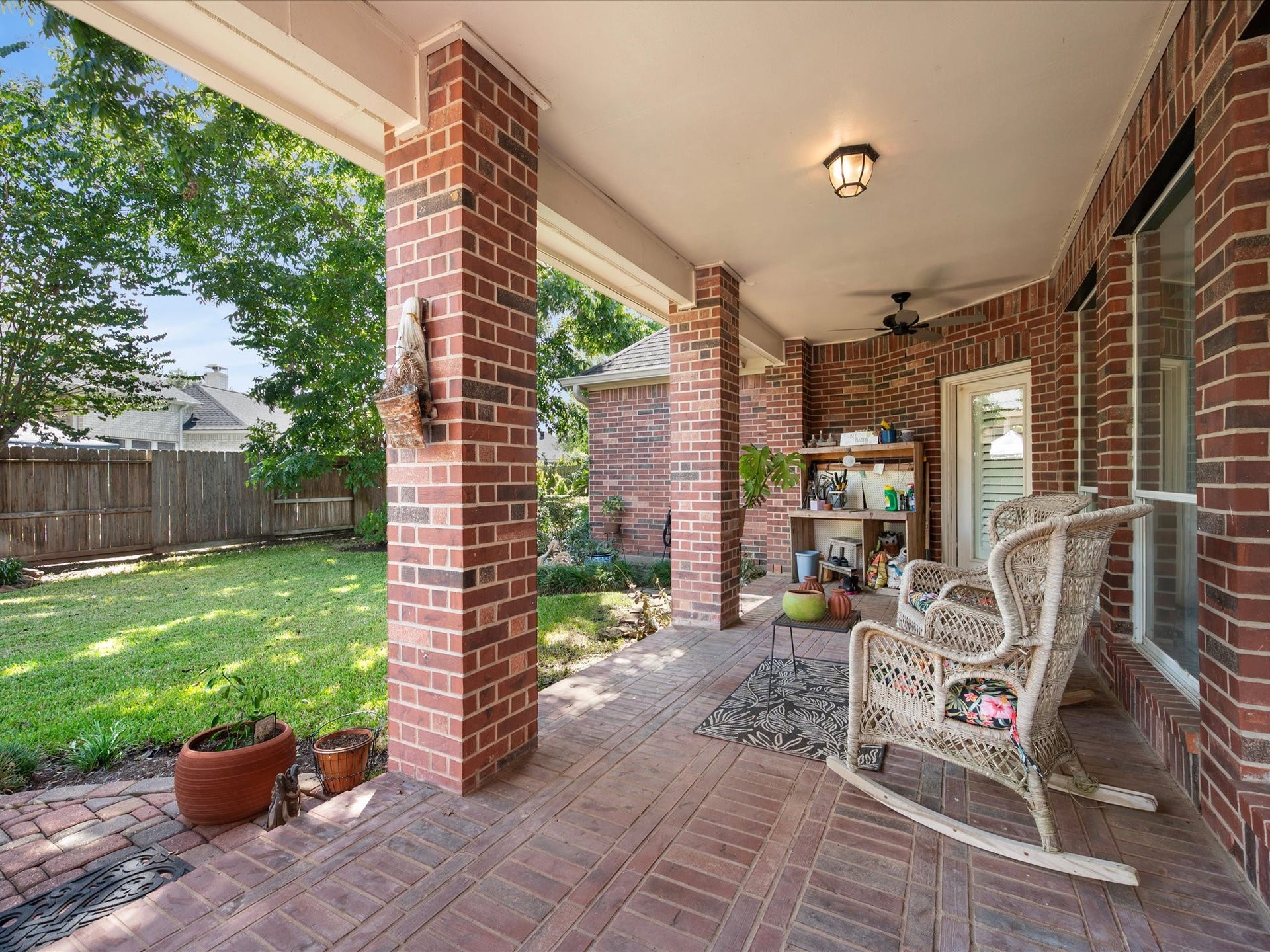 1834 Lake Quitman Drive, Richmond, TX 77406 Spacious covered back patio with brick pavers, ceiling fan, and room to relax, overlooking a fenced backyard with a built in potting station for the gardener.