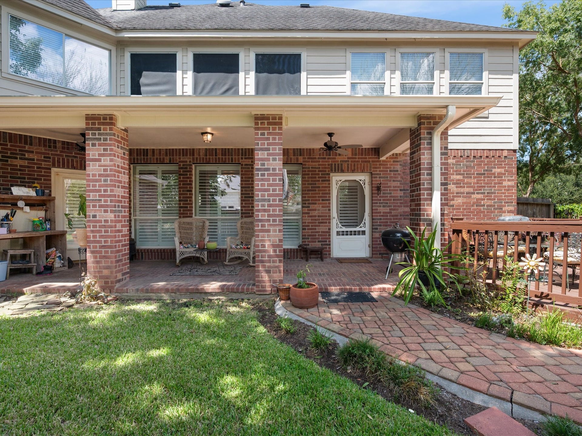 1834 Lake Quitman Drive, Richmond, TX 77406 Rear view of the home showcasing the covered back porch, brick paver walkway, and easy access to the backyard, with a screened door leading into the main living space.
