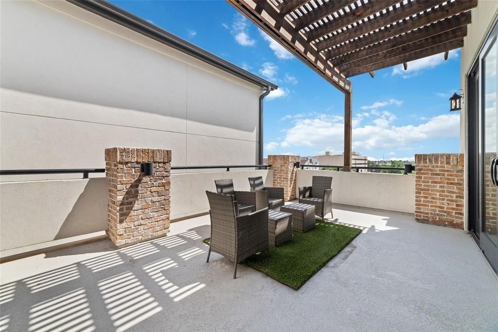 Spacious rooftop patio with a wooden pergola, brick accents ideal for relaxing or entertaining, with a mix of sun and shade.