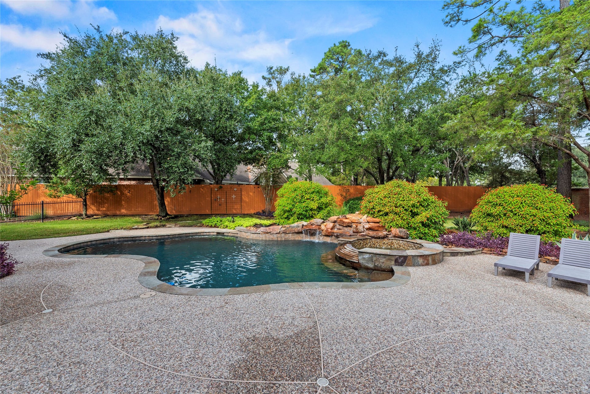 13915 Springmint Drive, Cypress, TX 77429 Freeform pool with cascading rock waterfall, raised spa, spacious decking and lush landscaping surrounded by mature trees.