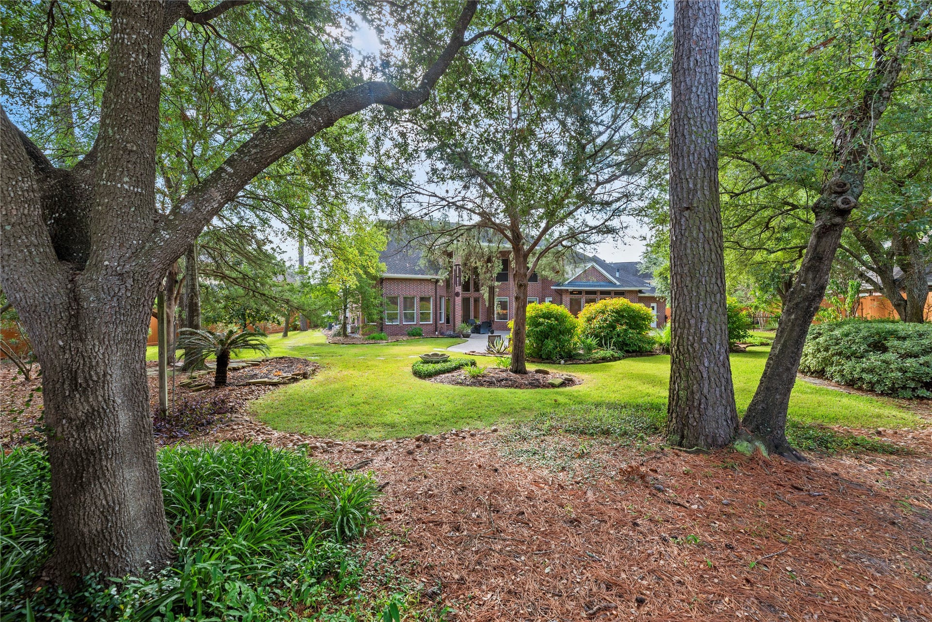 13915 Springmint Drive, Cypress, TX 77429 A picturesque view from the rear of the backyard showcases a park-like setting with towering mature trees, lush lawn and beautifully manicured landscaping, creating a serene and private retreat.