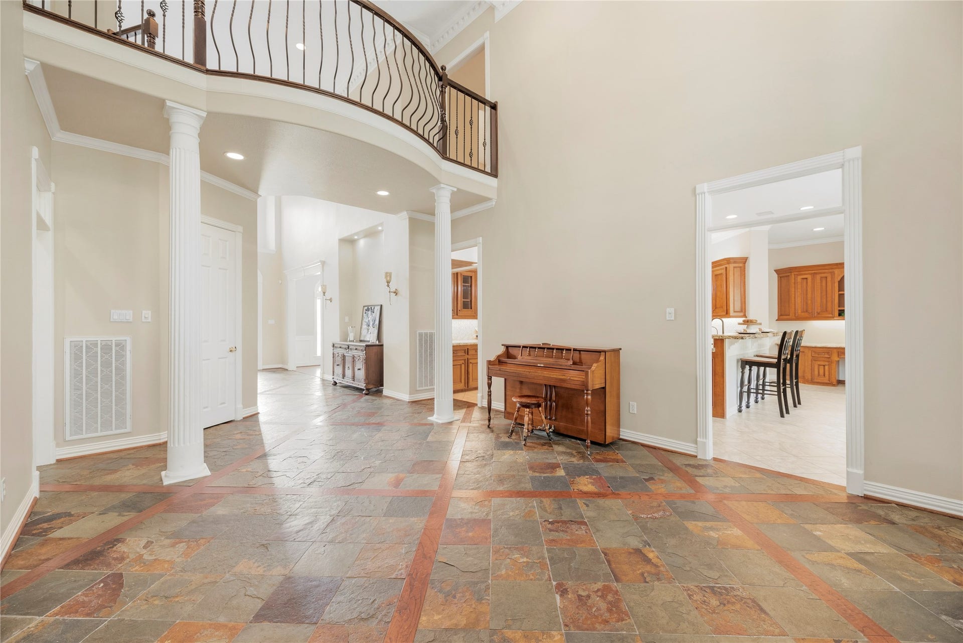 13915 Springmint Drive, Cypress, TX 77429 Impressive formal living room showcases a graceful curved balcony with decorative wrought iron railing, stately columns, elegant architectural detailing and rich slate flooring.