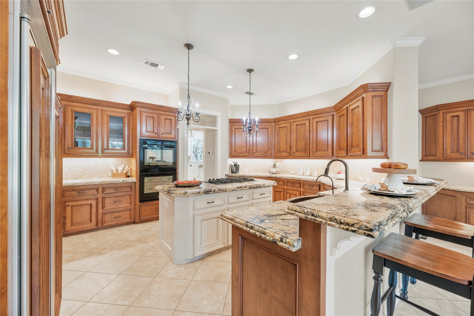 13915 Springmint Drive, Cypress, TX 77429 Exquisite gourmet kitchen showcases rich custom-style wood cabinetry, built-in side-by-side refrigerator, granite countertops, elegant tile backsplash, under cabinet lighting, pendant lighting, double ovens and a gas cooktop.
