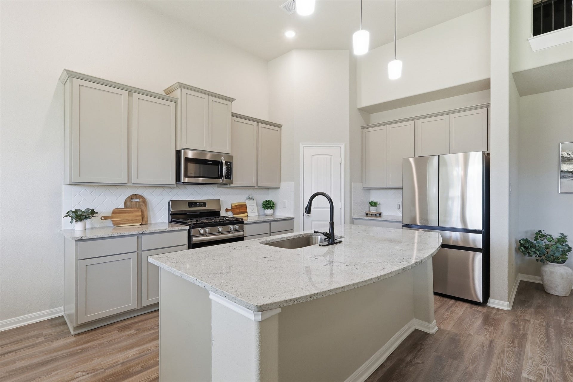 Stunning kitchen with upgraded granite countertops and backsplash, stainless steel appliances, modern cabinetry, and a large island, perfect for gathering and entertaining.