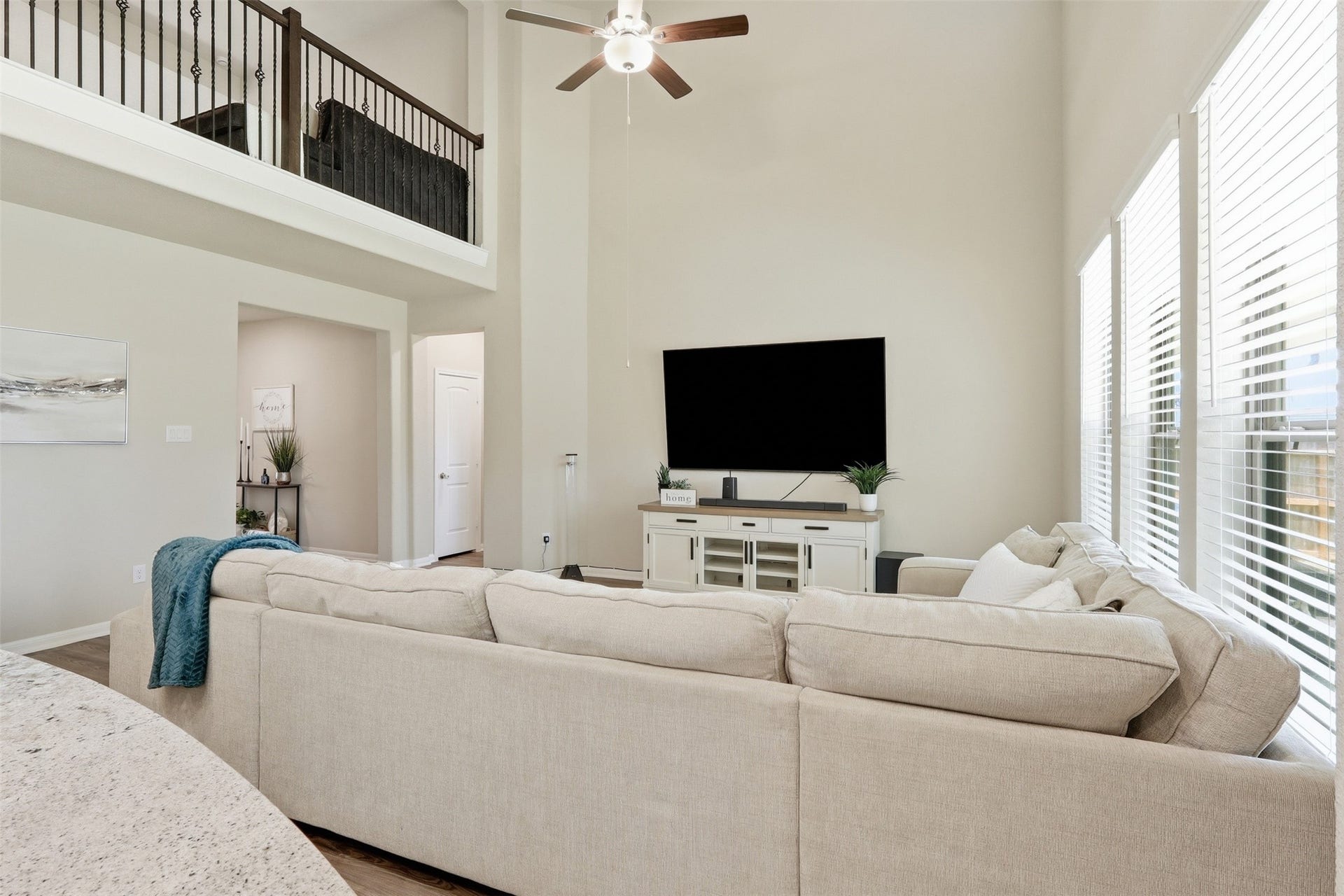 Bright and airy living room featuring soaring ceilings, expansive windows, and an open view to the upstairs game room, creating a spacious and inviting atmosphere.