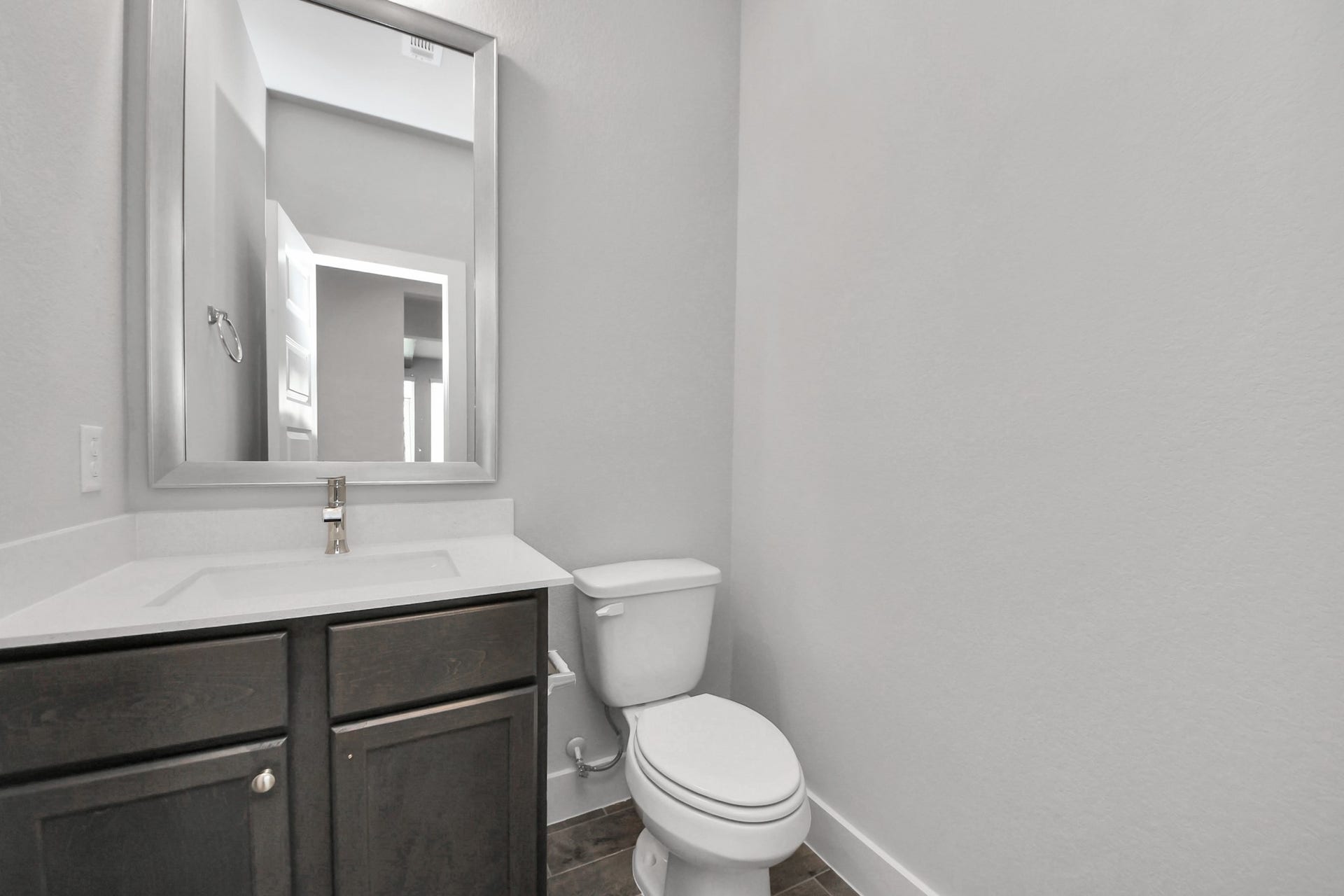 3213 Skerne Spring Drive, Spring, TX 77373 Sophisticated half bathroom adorned with contemporary finishes. The elegant 5-panel door welcomes you to a space where style meets functionality. Notice the sleek hardware accents that add a touch of modern charm. The vanity boasts light-colored countertops, beautifully complemented by a tasteful vanity light, creating a well-lit and inviting atmosphere. Sample photo of completed home with similar floor plan. Actual colors and selections may vary.