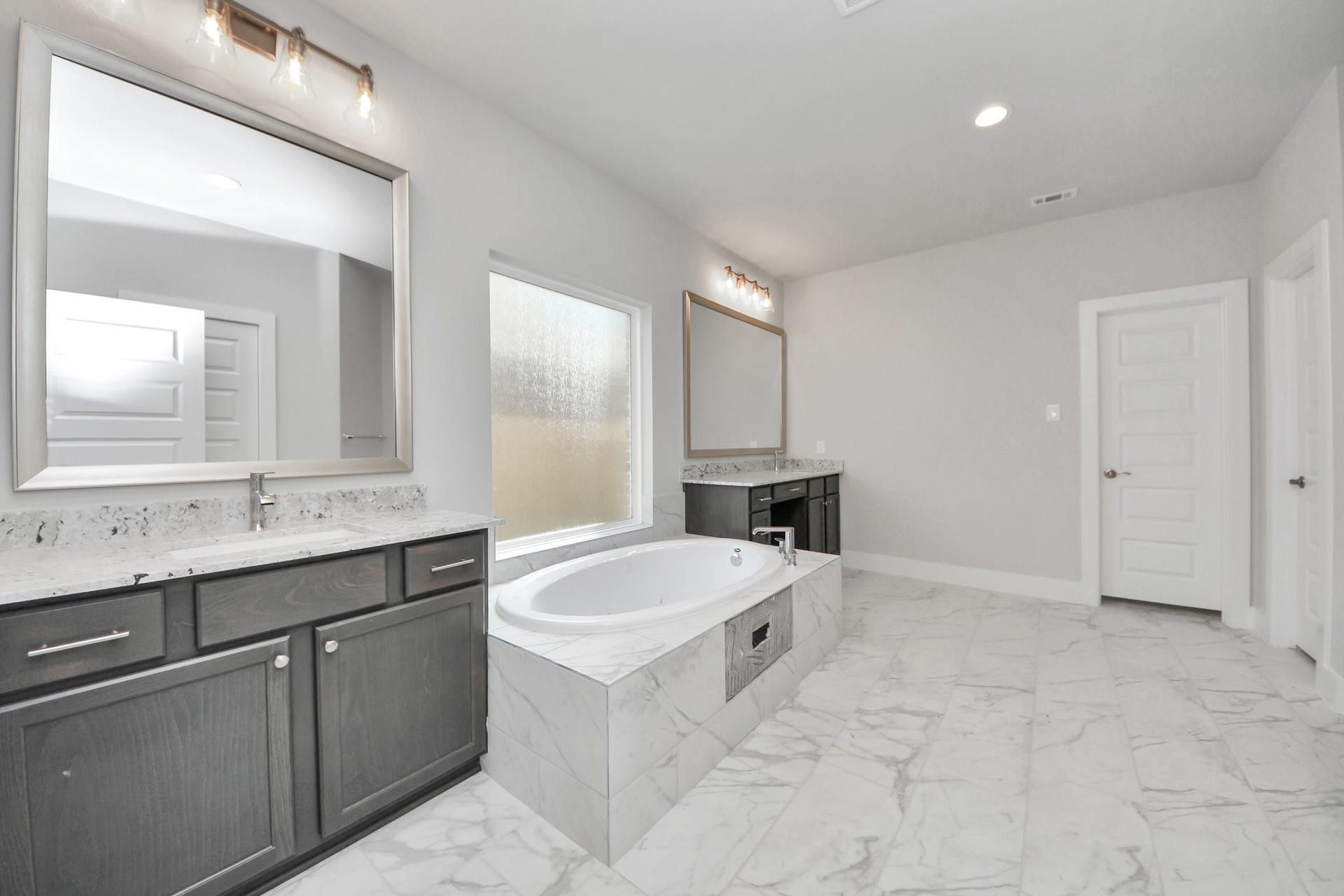 3213 Skerne Spring Drive, Spring, TX 77373 Escape to a spa-like oasis in this primary bathroom. Enjoy a walk-in shower with tile surround, a separate garden tub with custom detailing, and an elegant vanity featuring light countertops, modern hardware, and beautiful vanity lights. Experience luxury and relaxation in every detail. Sample photo of completed home with similar floor plan. Actual colors and selections may vary.
