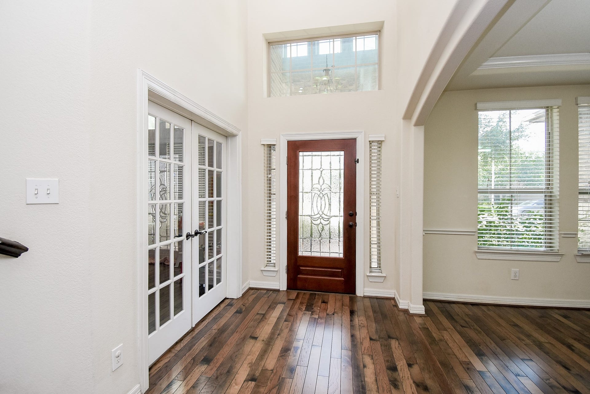 27807 Ashbrook Falls Court, Fulshear, TX 77441 Entryway has high ceilings, featuring a wooden front door with decorative glass, adjacent French doors to the office/study, and large windows providing natural light. Hardwood floors add warmth and elegance.