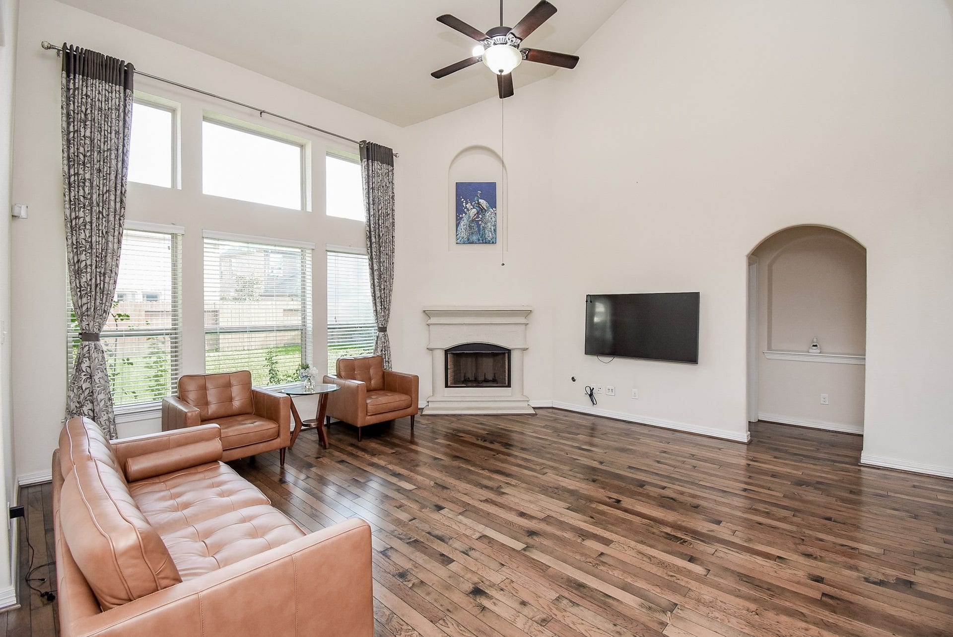 27807 Ashbrook Falls Court, Fulshear, TX 77441 The living room features high ceilings, large windows for ample natural light, and elegant wood flooring. It includes a cozy fireplace as well.