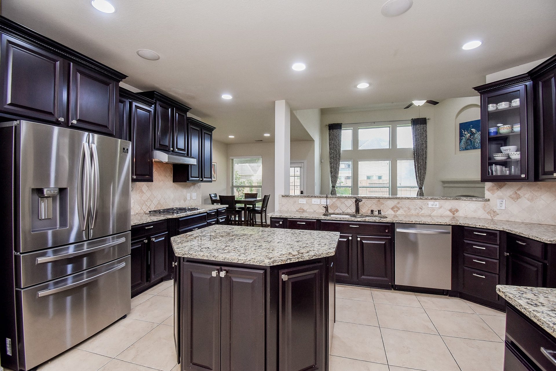 27807 Ashbrook Falls Court, Fulshear, TX 77441 Spacious kitchen features elegant dark wood cabinetry, granite countertops, and modern stainless steel appliances. A central island provides extra workspace.